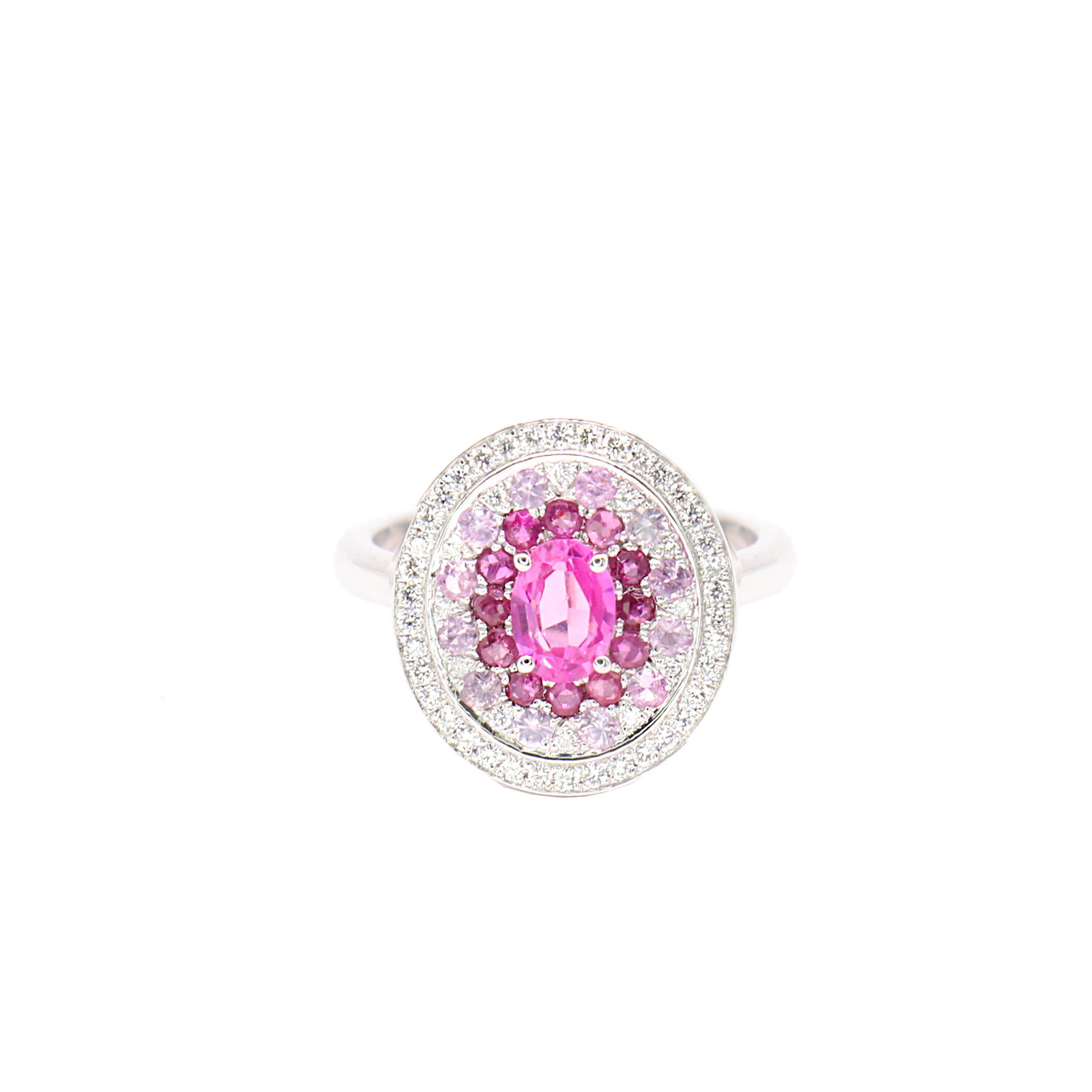 S.Georgios designer presents a captivating 18K White Gold Ring featuring a stunning oval-cut Pink Sapphire total weight of 0.96 Carats, at the center. Τhe center is surrounded by smaller pink sapphires which degrade in color total weight of 0.91