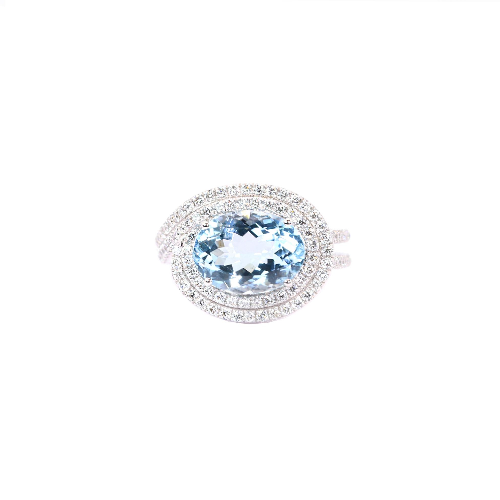 S.Georgios designer presents an exquisite 18K White Gold Ring featuring a large oval-cut Aquamarine totlal weight of 3.98 Carats surrounded by brilliant-cut Diamonds. The band is adorned with two lines of additional brilliant-cut Diamonds, creating