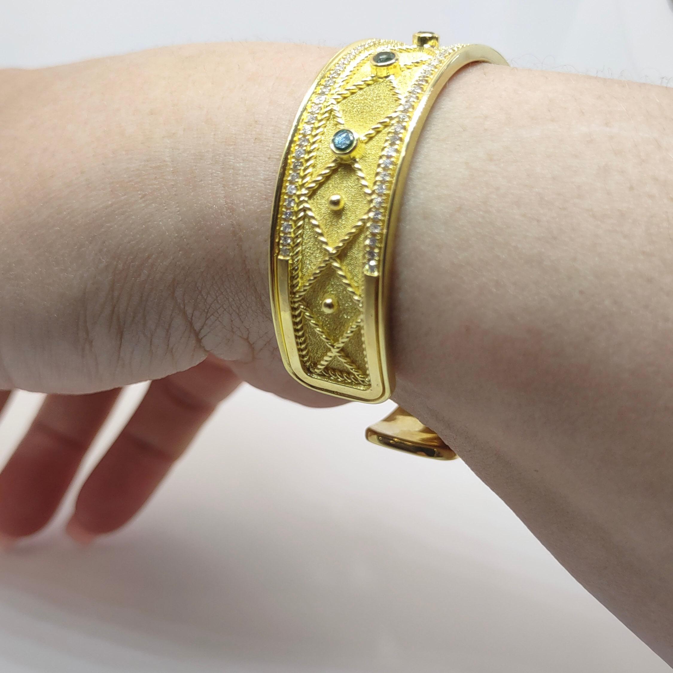 Der Designer S.Georgios präsentiert ein handgefertigtes Armreif-Armband aus 18 Karat Gelbgold. Dieses atemberaubende Armband ist mikroskopisch mit Granulationsarbeiten im byzantinischen Stil mit gedrehten Drähten und Perlen verziert, die im Kontrast