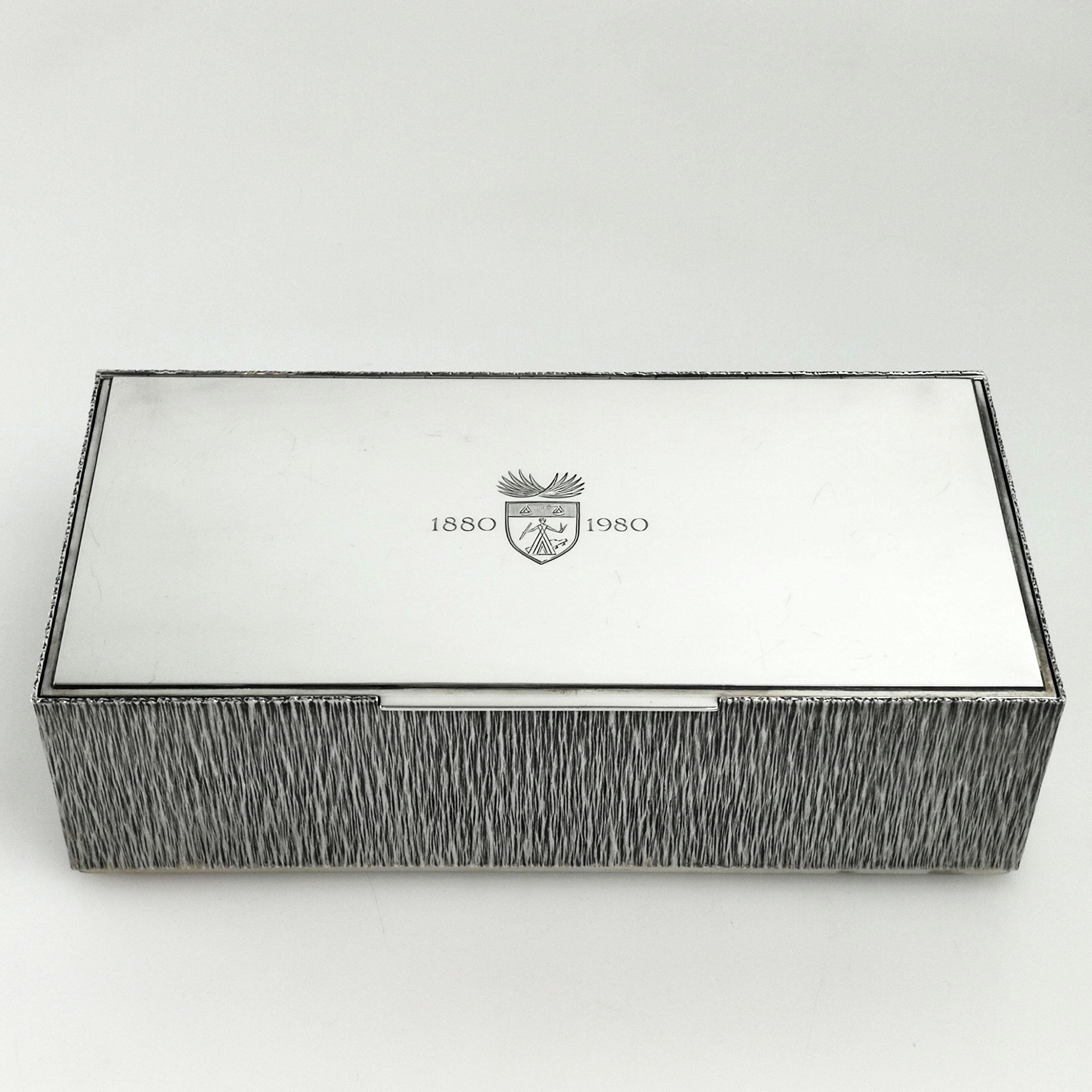 A gorgeous solid Silver Cigar Box by the acclaimed post war Silversmith Gerald Benney. An elegant rectangular Box with a bark effect on the sides and underside. The lid is polished silver with a small crests and the dates 1880-1980. The interior is