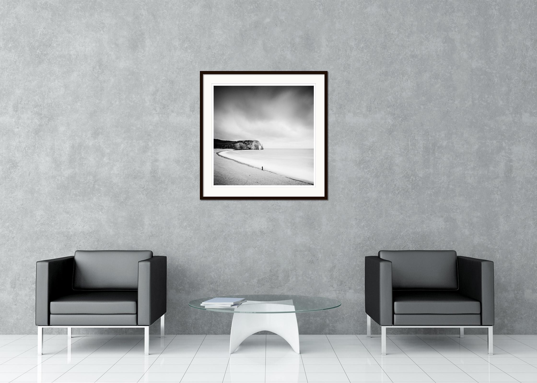 Black and white fine art landscape photography. Beautiful beach with fishermen and the impressive rock formation of Etretat, France.. Archival pigment ink print as part of a limited edition of 9. All Gerald Berghammer prints are made to order in