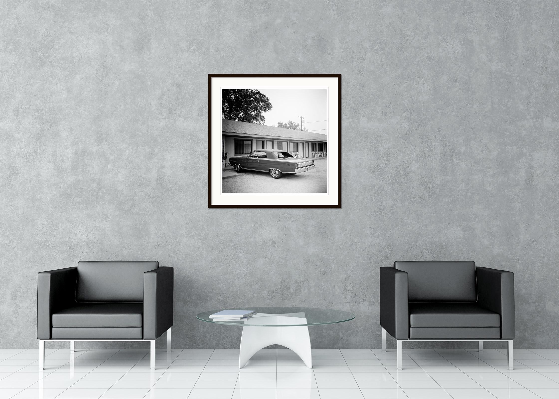 Photographie de paysage en noir et blanc.  Voiture classique Plymouth 1967 devant un motel sur la route 66, USA. Tirage à l'encre pigmentaire d'archives faisant partie d'une édition limitée à 9 exemplaires. Tous les tirages de Gerald Berghammer sont