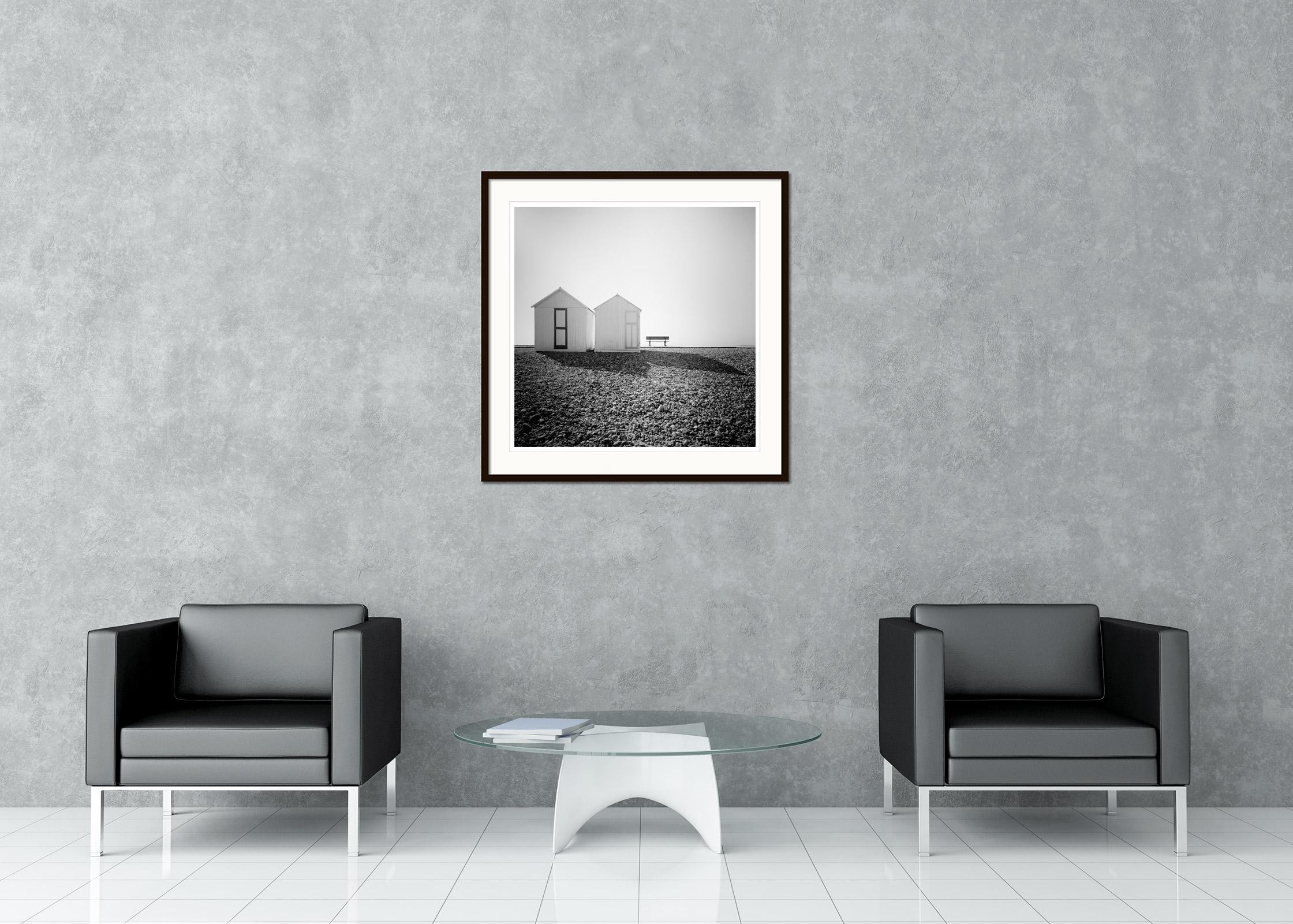 Black and white fine art landscape photography. Romantic beach huts with a bench on the stony beach of France. Archival pigment ink print, edition of 9. Signed, titled, dated and numbered by artist. Certificate of authenticity included. Printed with