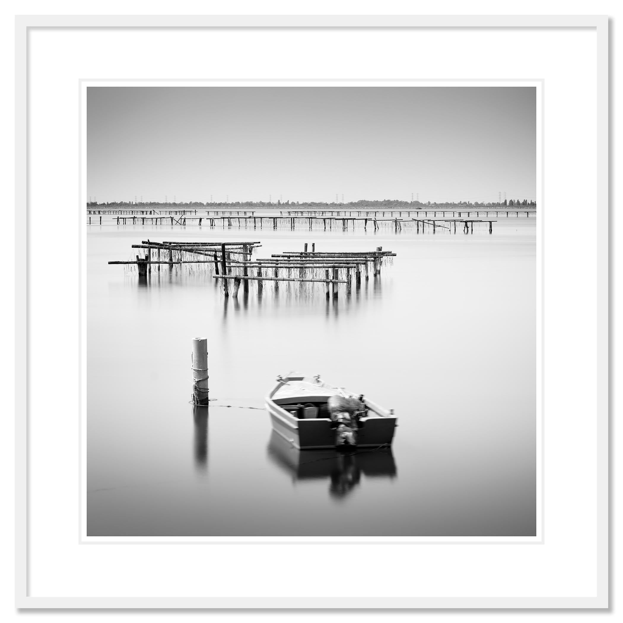 Photographie de paysage et de paysage aquatique en noir et blanc, avec une longue exposition. Aquaculture avec bateau de pêche dans la réserve naturelle du delta du Pô, Italie. Épreuve à l'encre pigmentaire d'archives, édition de 7 exemplaires.