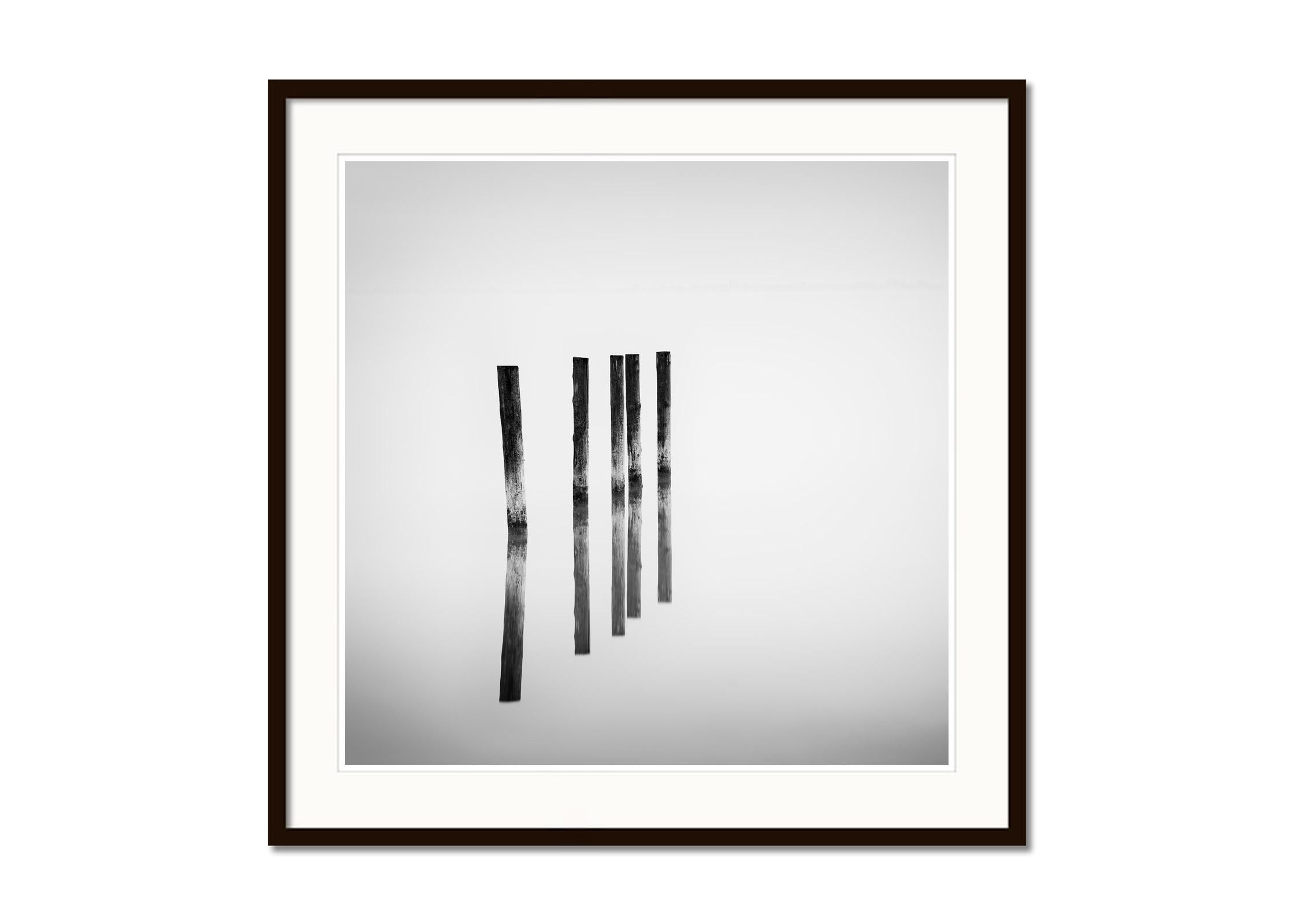 Cinco postes de madera, Lago, larga exposición, fotografía de paisaje acuático, edición limitada - Black and White Photograph Negro de Gerald Berghammer