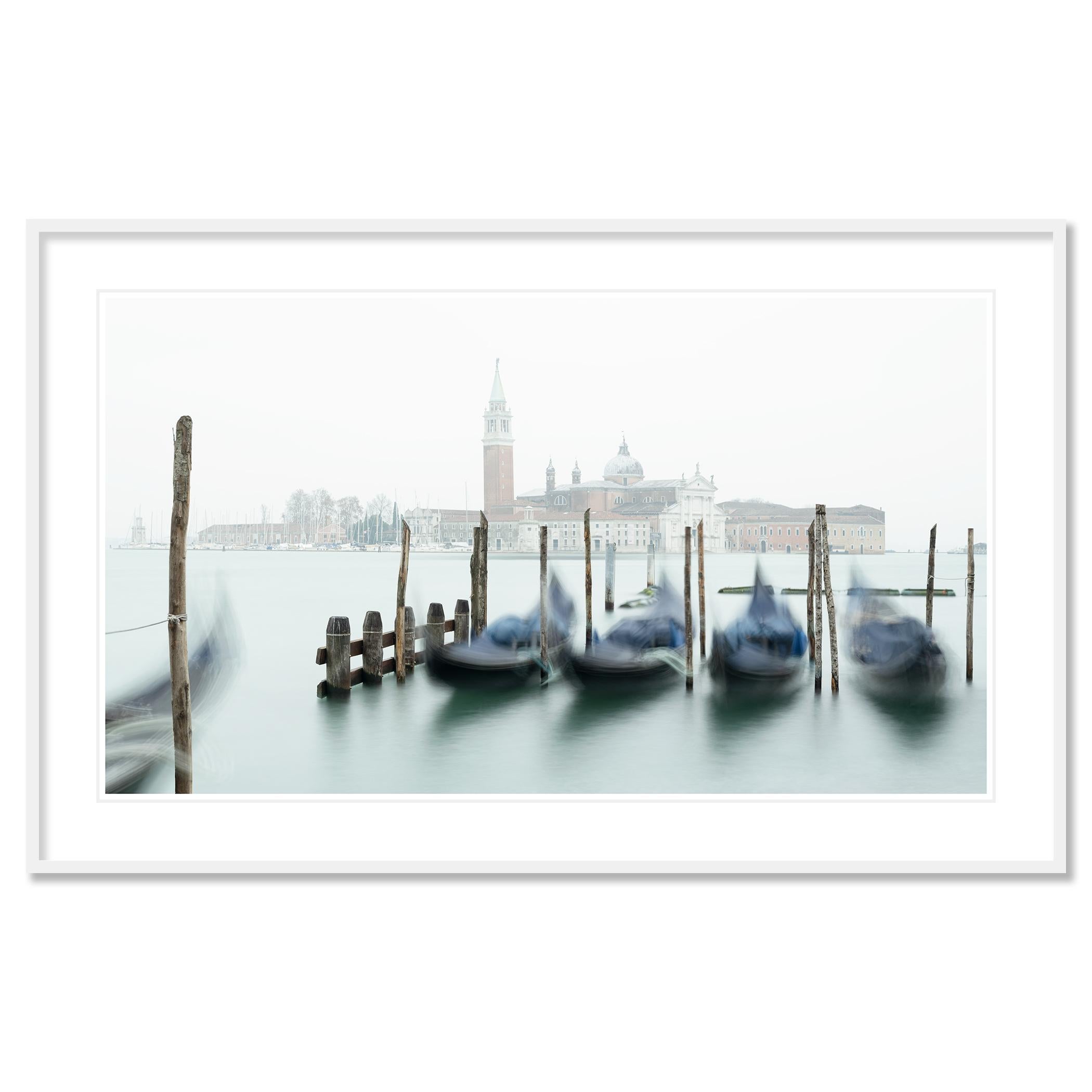 Gerald Berghammer - Photographie de paysages urbains en couleur. Les gondoles sont amarrées le long de poteaux en bois sur un canal d'eau brumeux et à l'arrière l'église San Giorgio Maggiore.

Tous les tirages de Gerald Berghammer sont réalisés sur