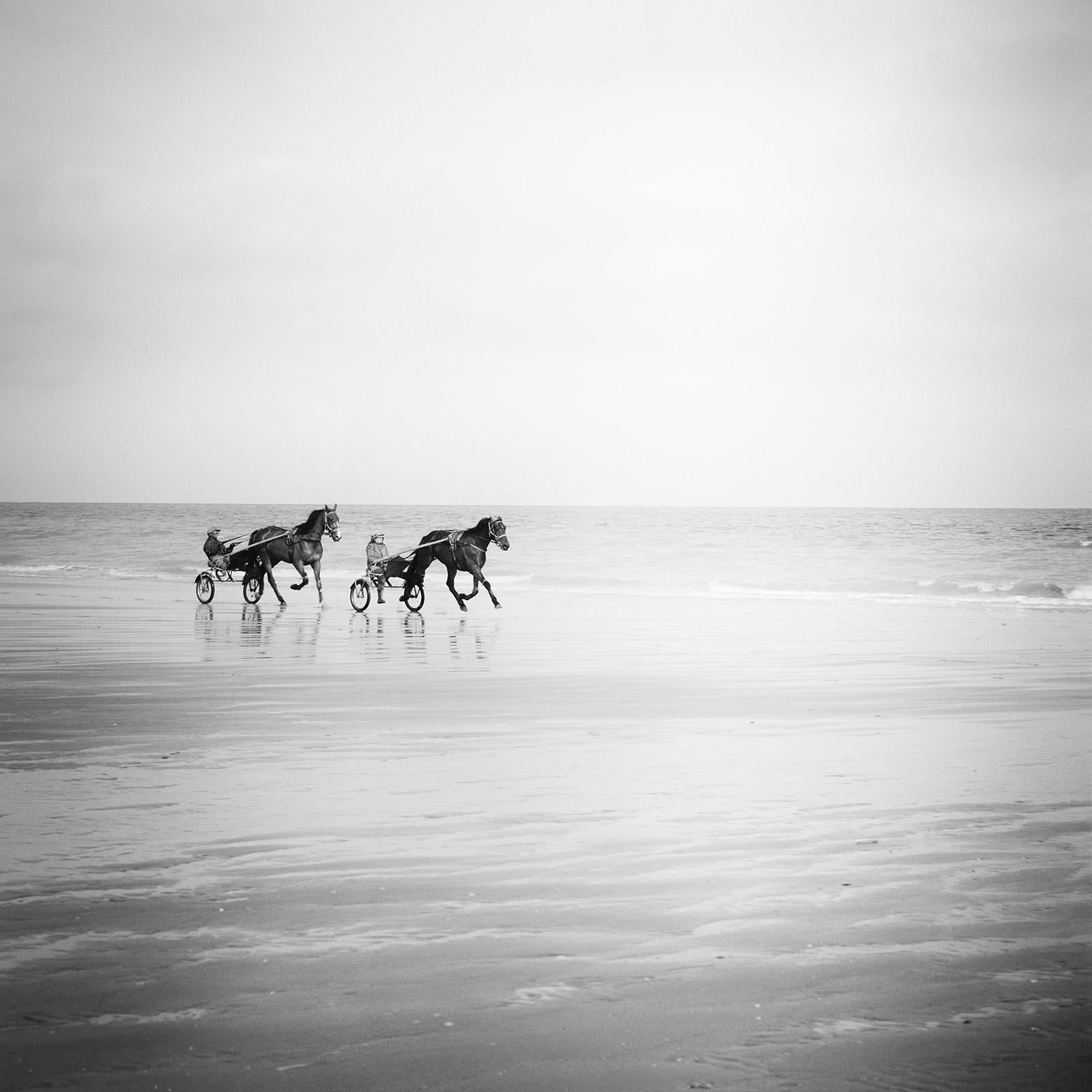 Gerald Berghammer Landscape Photograph – Harness Racing, Pferde am Strand, Frankreich, Schwarz-Weiß-Landschaftsfotografie