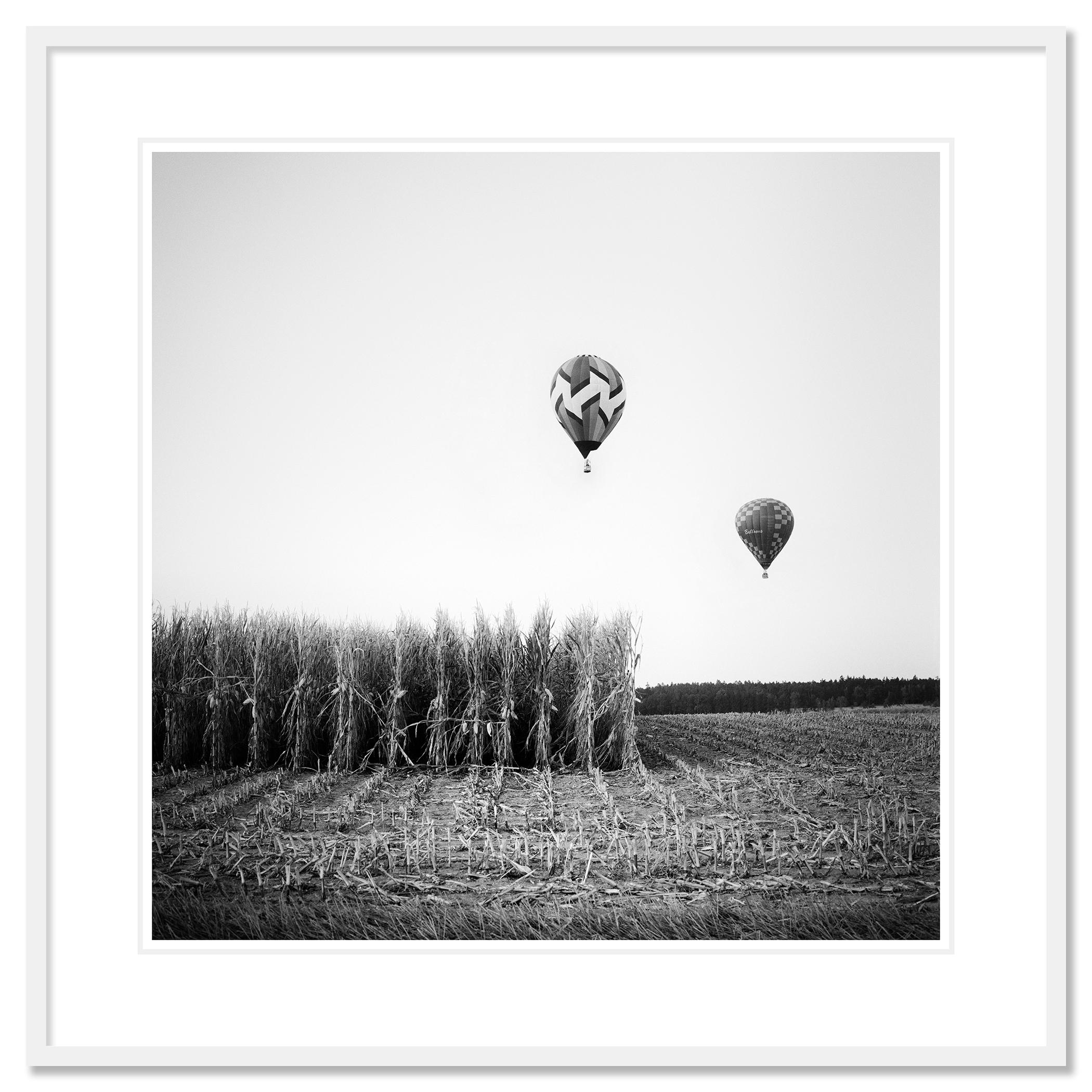 Tirage photographique d'art en noir et blanc. Deux montgolfières au-dessus d'un champ de maïs pendant la coupe du monde en Autriche. Épreuve à l'encre pigmentaire d'archives, édition de 9 exemplaires. Signée, titrée, datée et numérotée par