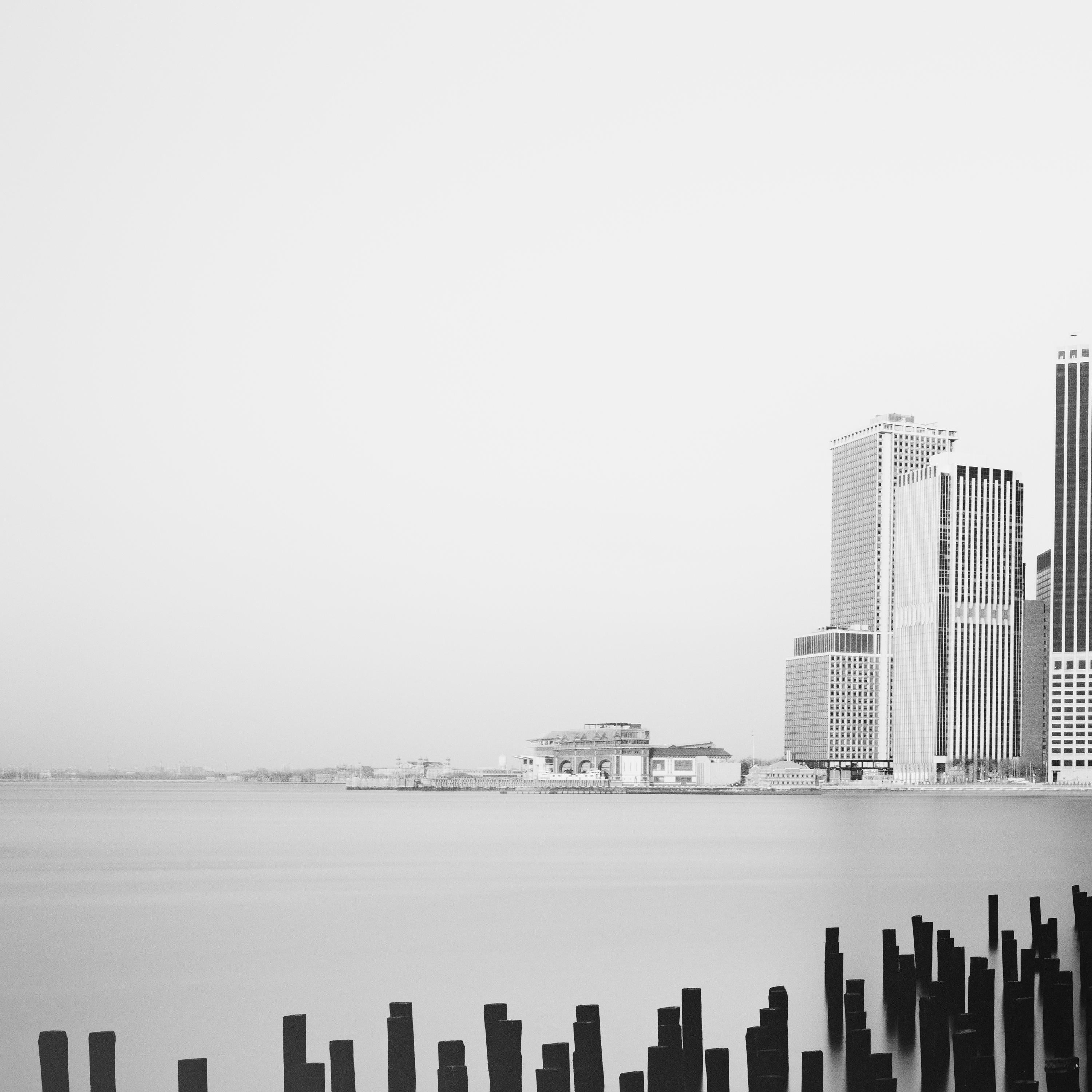 Black and white fine art long exposure waterscape - landscape photography. Manhattan skyline with breakwater in foreground, New York city, USA. Archival pigment ink print as part of a limited edition of 9. All Gerald Berghammer prints are made to