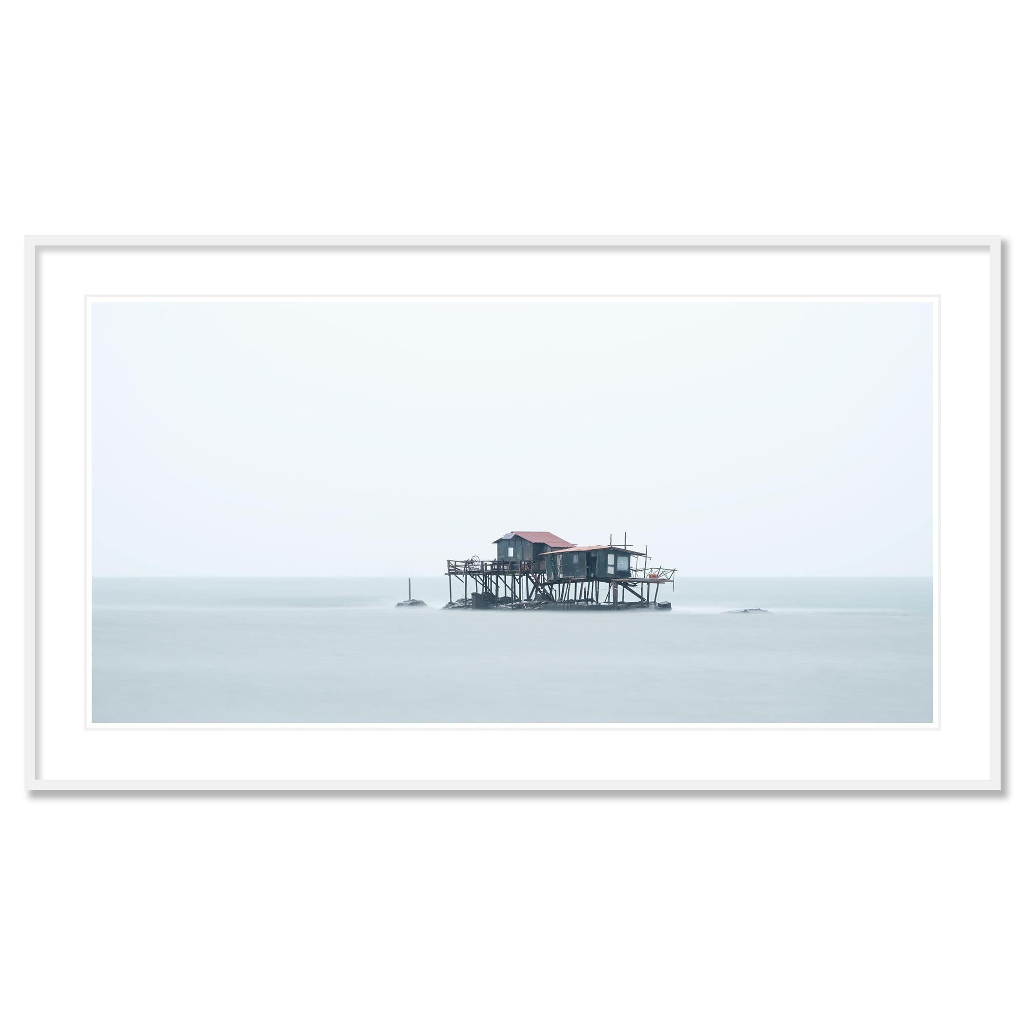 Gerald Berghammer - Color long exposure seascape photography. A small house on stilts stands over calm water on a foggy day, with a light sky.

Archival pigment ink print as part of a limited edition of 7. 
All Gerald Berghammer prints are made to