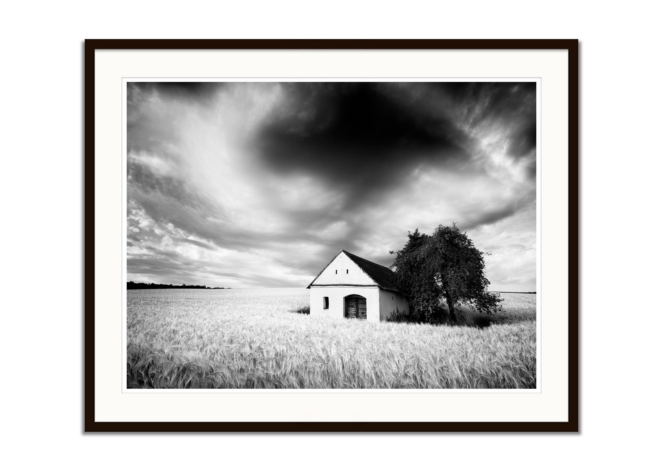 Wine Press House, wheat field, heavy cloud, black & white landscape photography - Gray Black and White Photograph by Gerald Berghammer