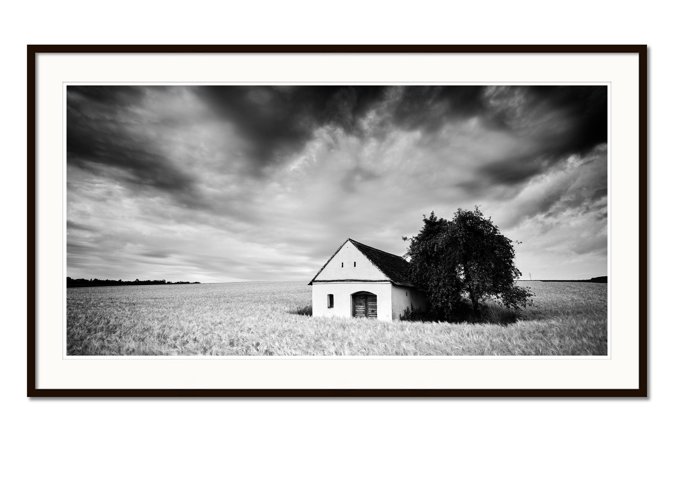 Black and white fine art long exposure landscape photography. Lonely wine press house in the corn field with spectacular clouds, Weinviertel, Austria. Archival pigment ink print, edition of 7. Signed, titled, dated and numbered by artist.