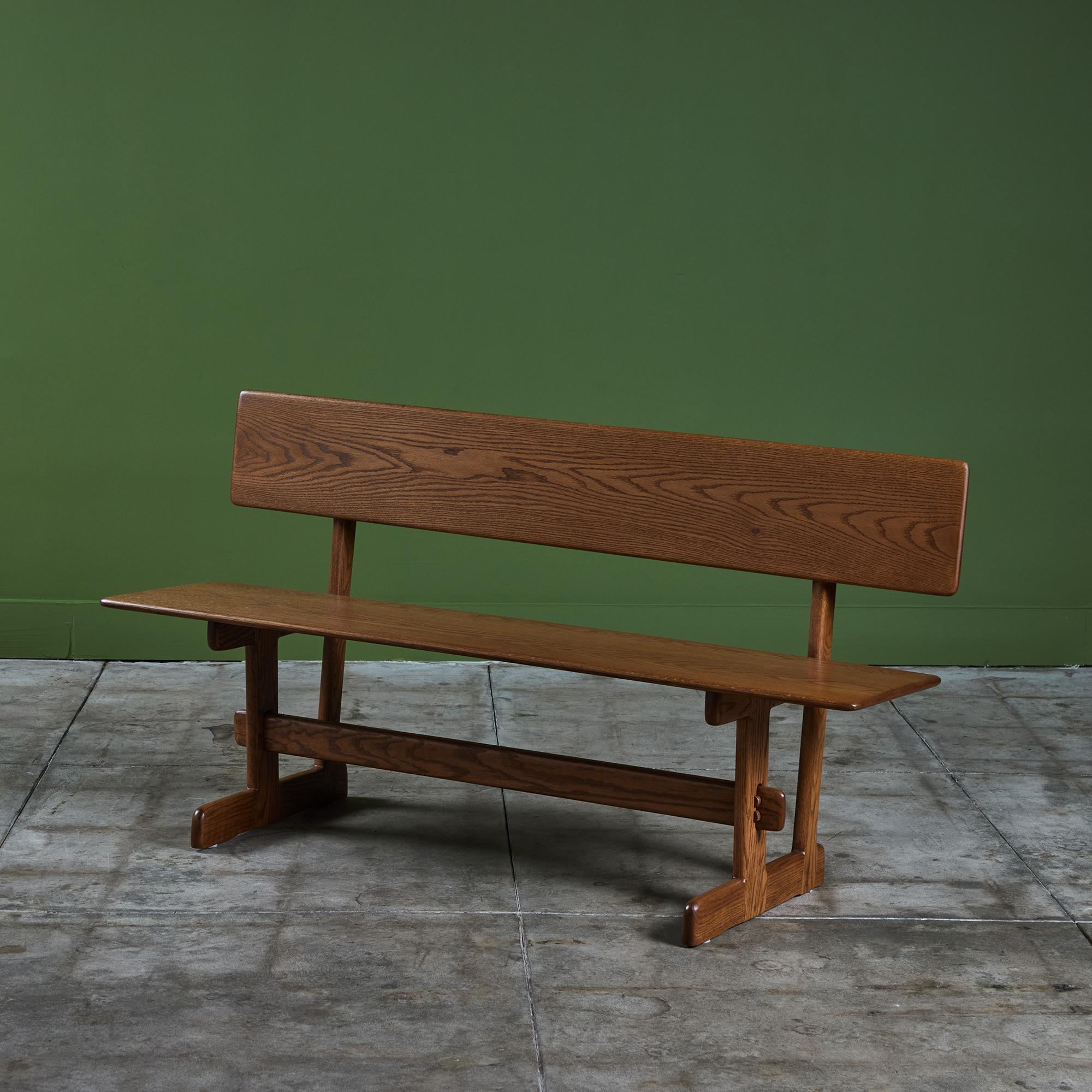 Oak bench from American designer Gerald McCabe for Eon Furniture, c.1970s. The solid wood bench has a long seat with seat back perfect for a dining table, living room or entry way. Pairs beautifully with the Gerald McCabe Oak Trestle Dining