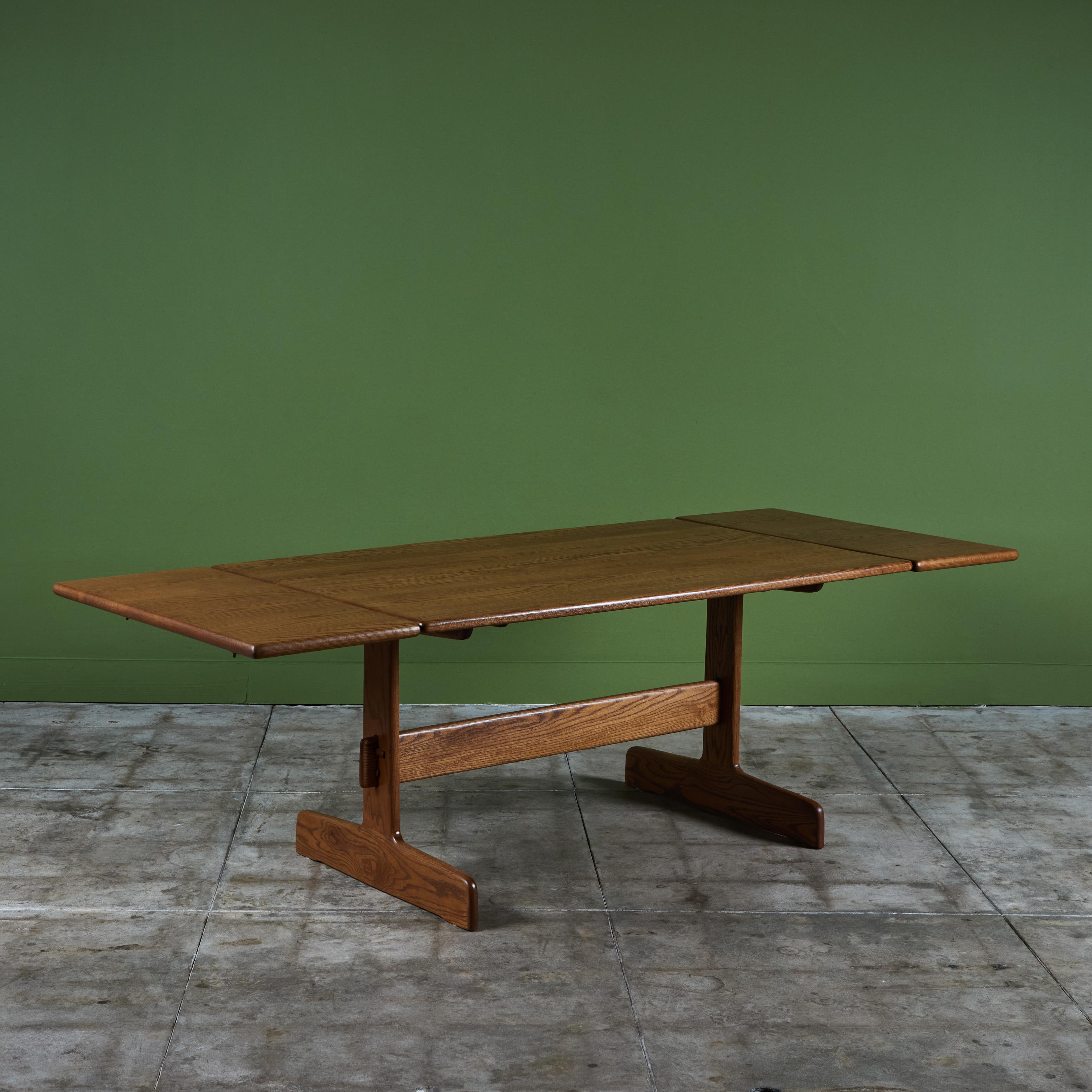 Oak dining table from American designer Gerald McCabe for Eon Furniture, c.1970s. The solid wood table has two leaves which attach on either end of the table. The table looks beautiful paired with the available Gerald McCabe Trestle