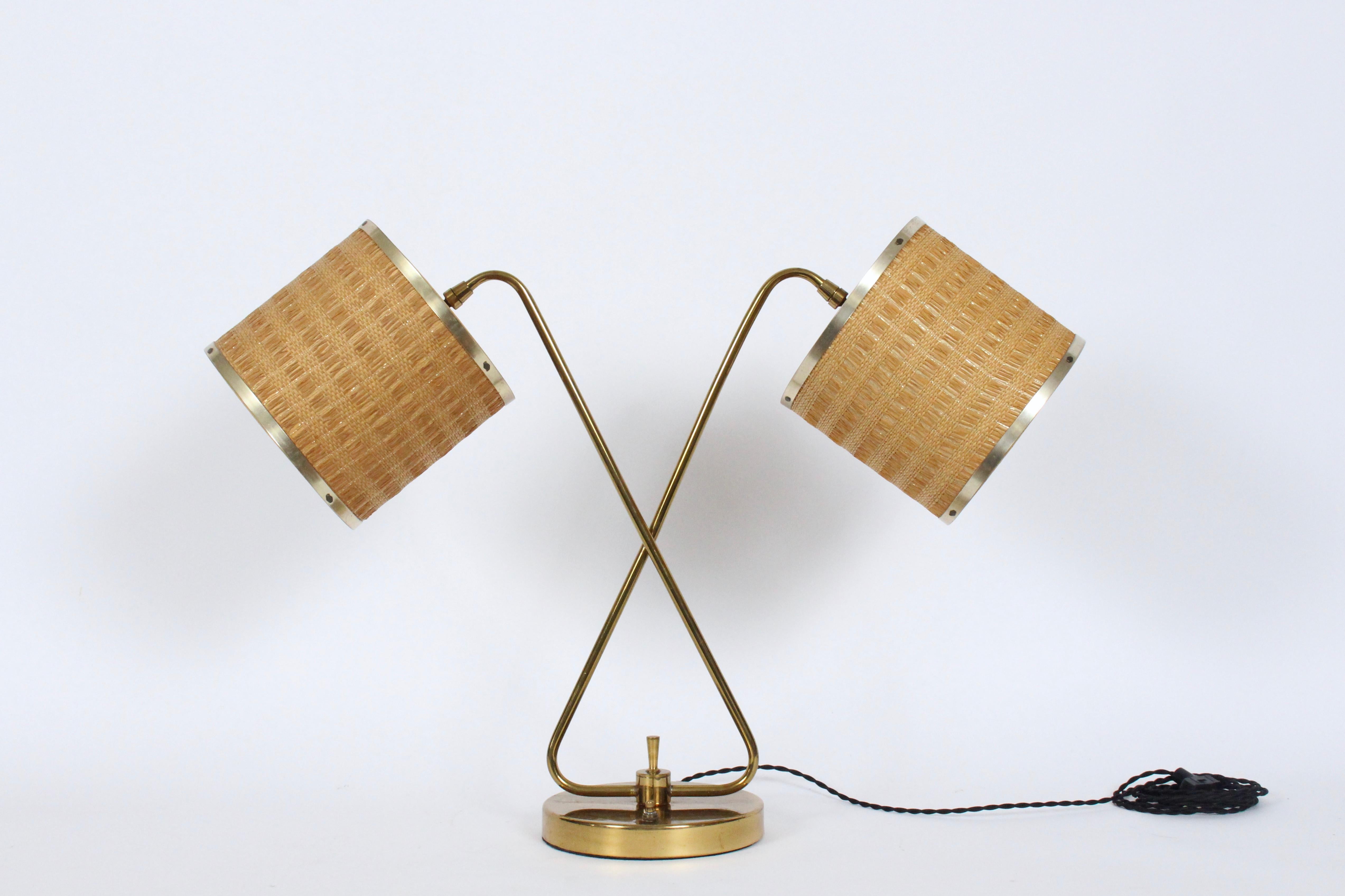 Gerald Thurston for Lightolier crossed swords desk lamp with brass rimmed Raffia Barrel Shades.  Featuring dual arms in Brass, ball sockets, original adjusting dual Brass rimmed intertwined Raffia ribbon 7 H x 7 D barrel lampshades, a top a circular