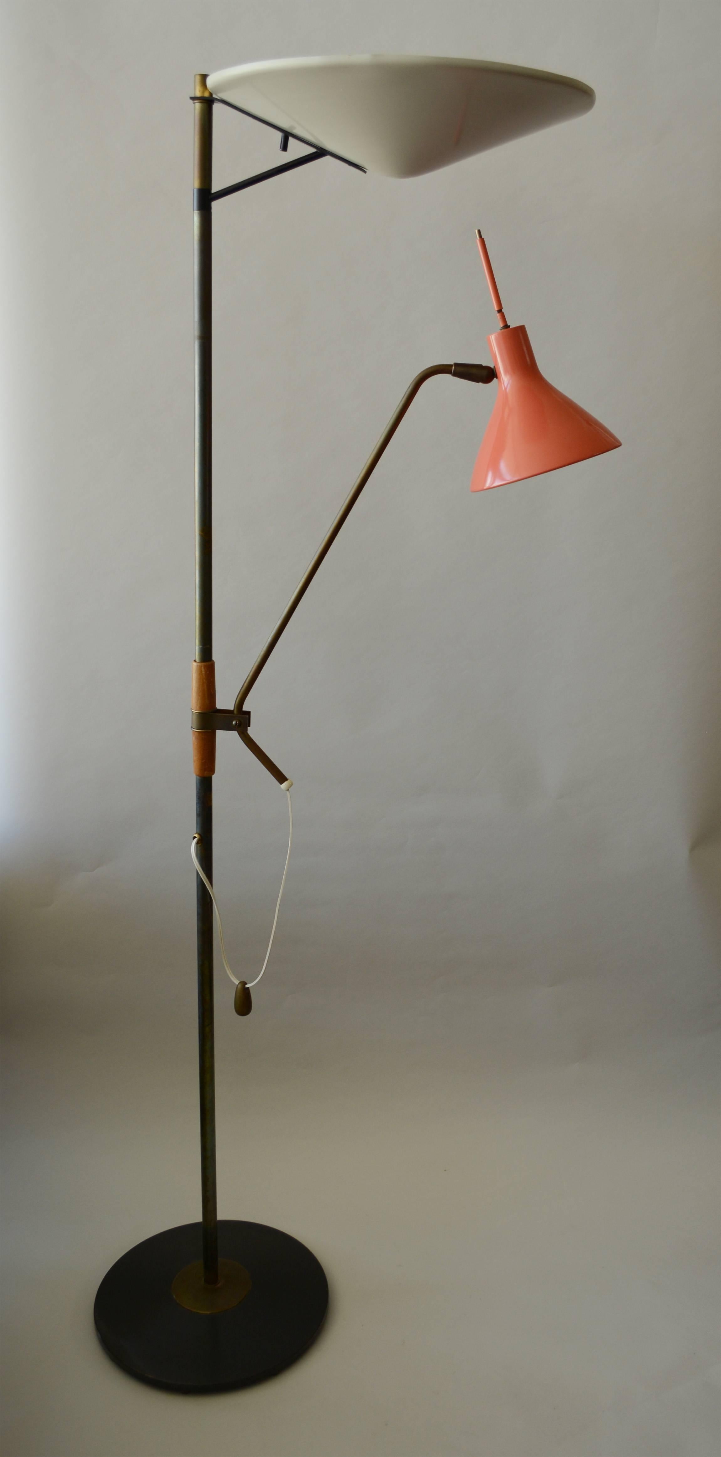 This versatile floor lamp designed by Gerald Thurston has an upward reflector and an adjustable reading lamp. The lamp was manufactured by Lightolier. The brass has a dark patina. The wood on the column shows some wear and has a crack in it.