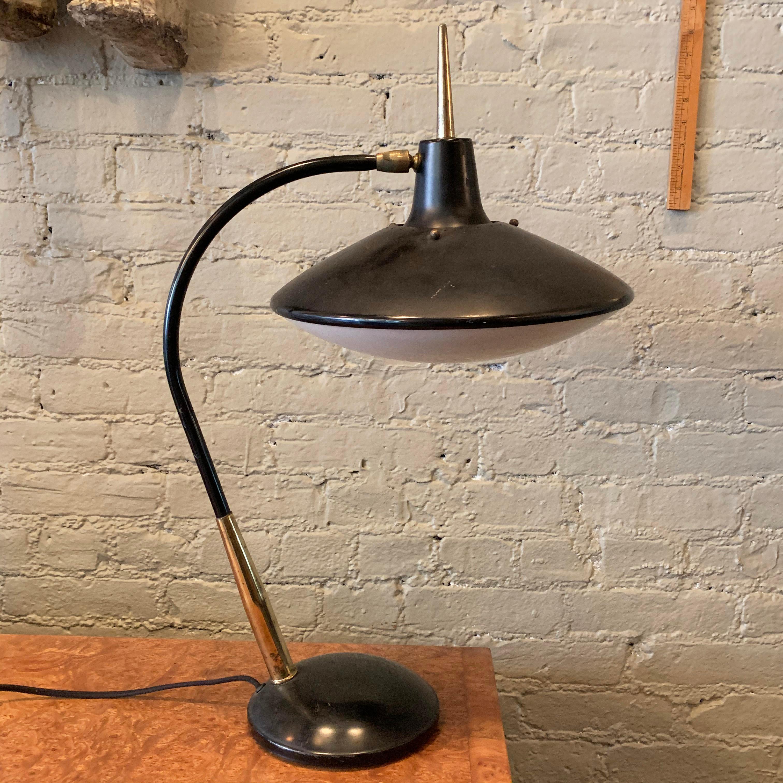 Mid-Century Modern, desk lamp by Gerald Thurston for Lightolier features an articulating, 12 inch diameter, spun aluminum with Lucite diffuser saucer shade on an arched stem with brass detail. The base is 7 inch diameter.