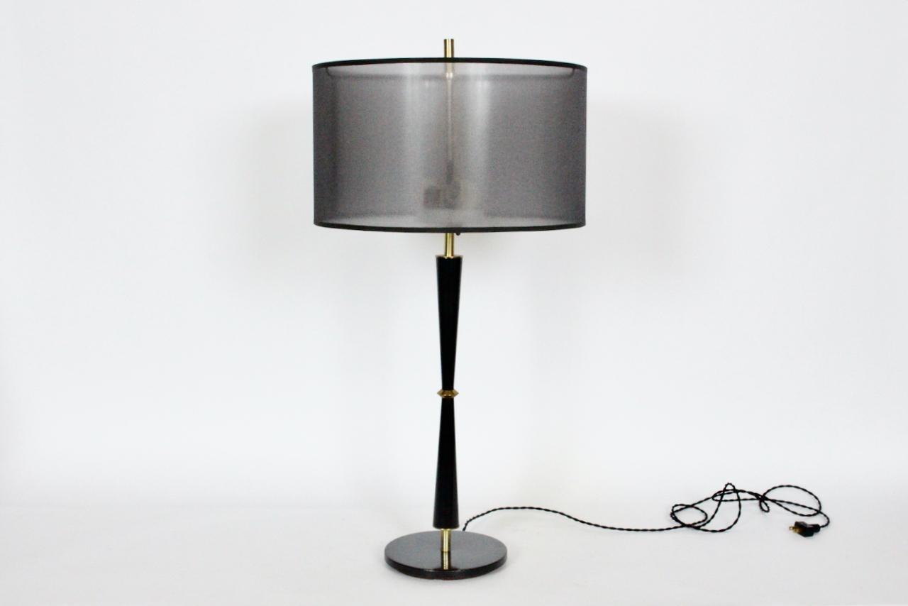 Sleek American midcentury Gerald Thurston for Lightolier black enameled table lamp with brass details. Featuring a slender all black enameled metal hourglass stem, elevated above a round 7.5D Black enameled balanced base supported by a weighted Cast