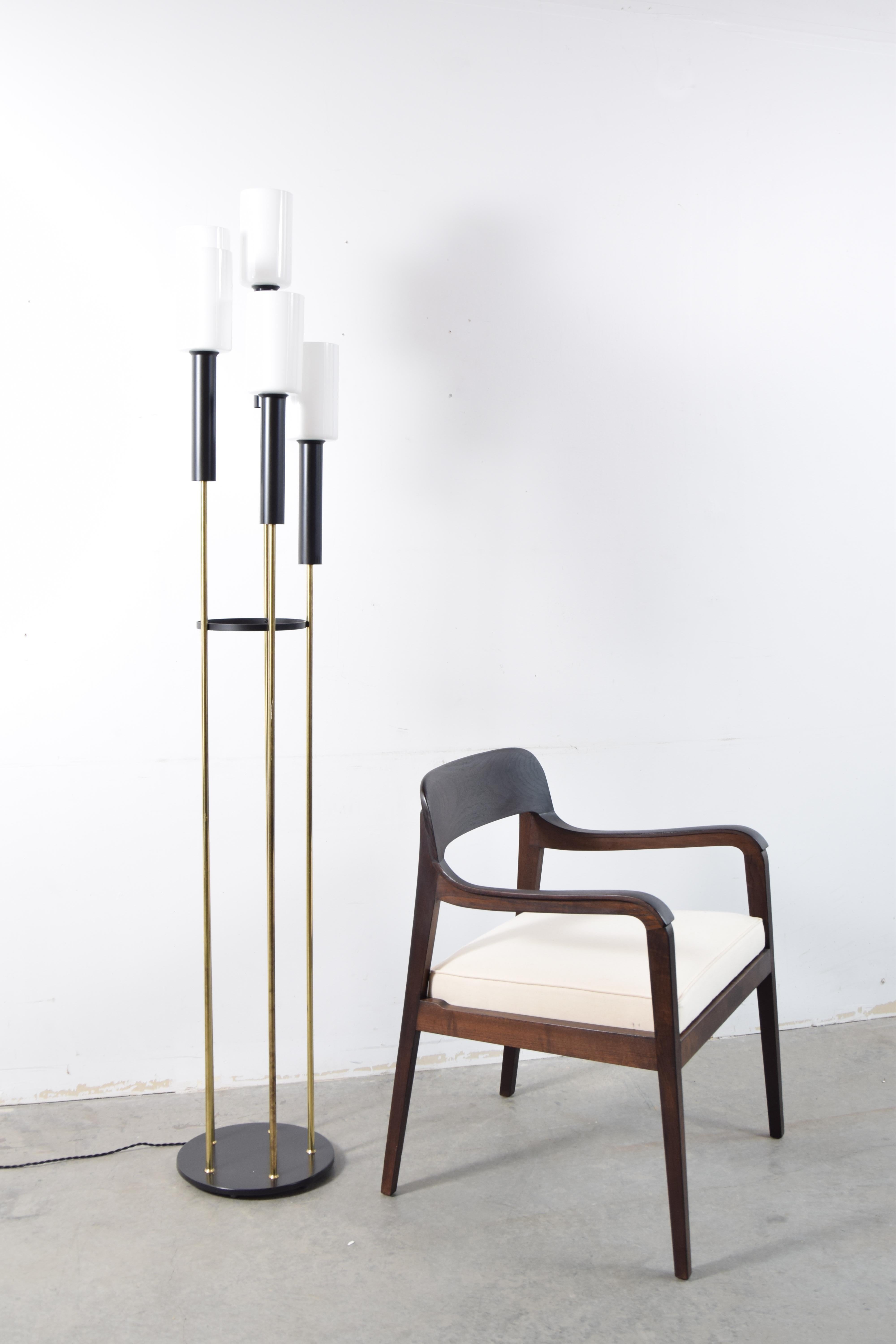 Floor lamp designed by Gerald Thurston for Lightolier, circa 1955. Lamp consists of five brass rods of graduated lengths, held together by a black steel ring, sitting on a round black metal base, topped with black metal tubes that hold five white