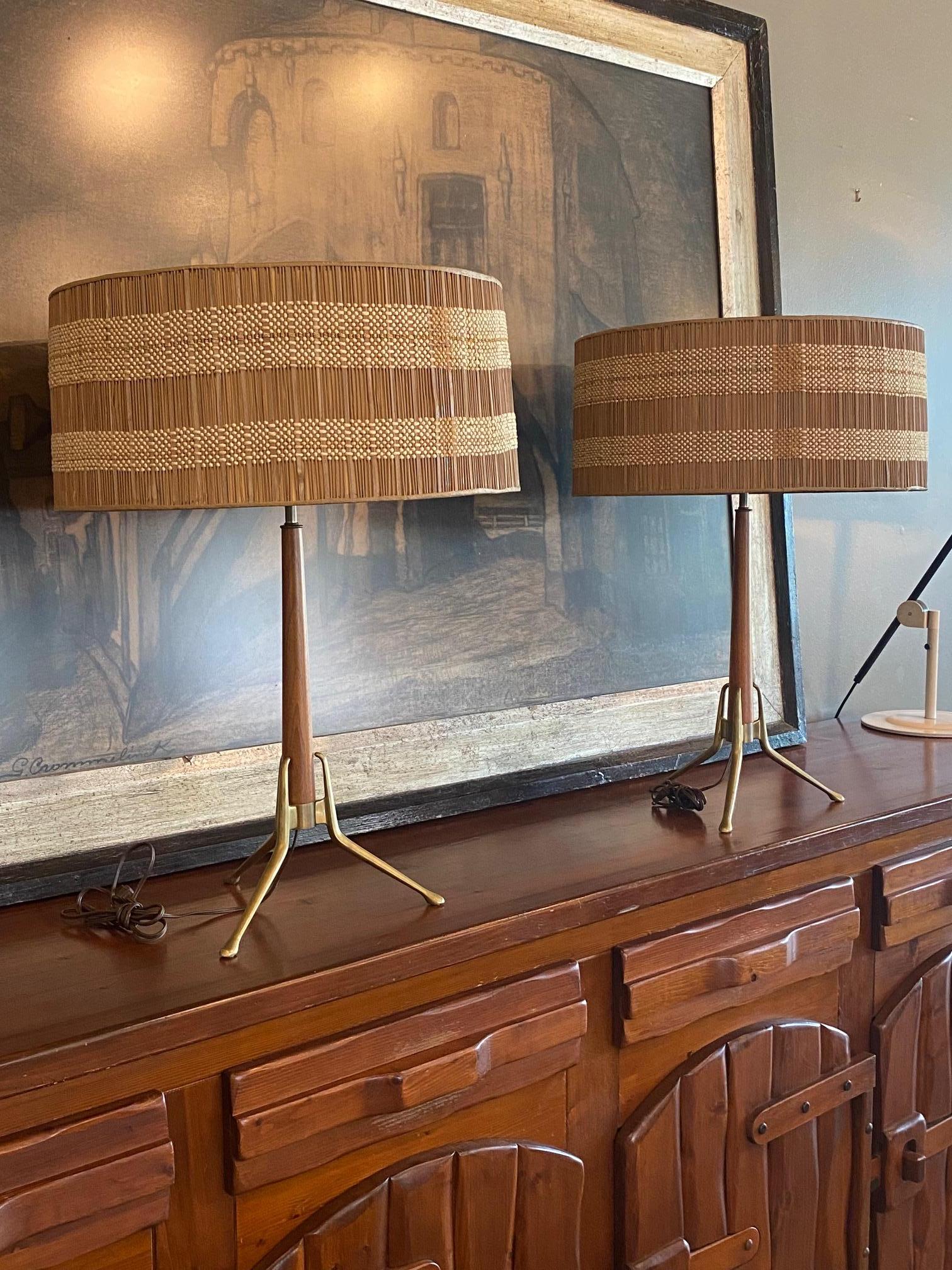 Gerald Thurston For Lightolier tripod mid century modern table lamps. Original matched pair of brass and walnut lamps retain perforated metal disc diffusors and outfitted with original Maria Kipp period lamp shades. Three bulb socket fixture allows
