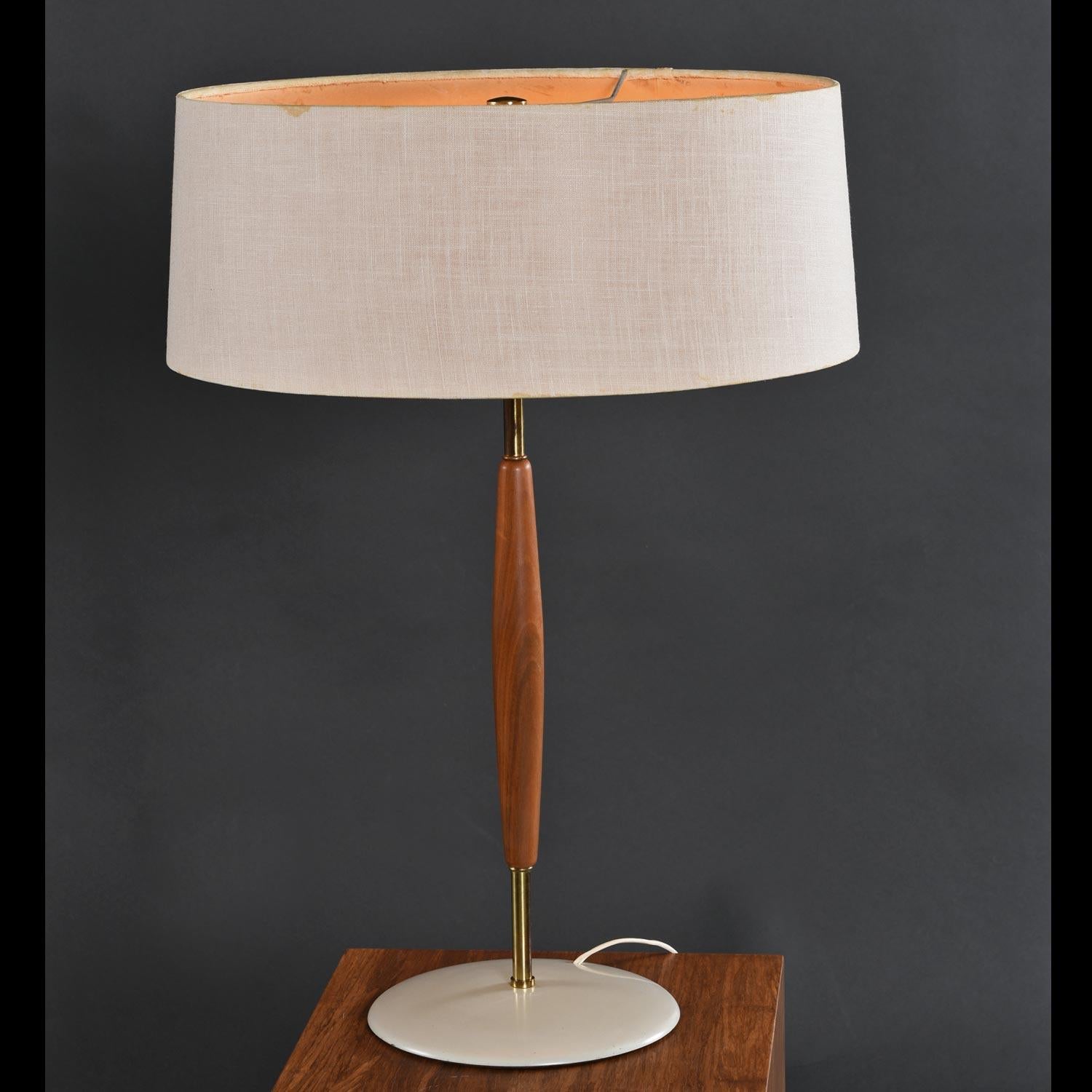 Vintage 1950s table lamp by Gerald Thurston for Lightolier. The lamp is comprised of a brass rod embellished with an elegantly tapered wood mid-section. The wood is so beautifully turned that it’s a challenge to decipher just what species it is. The