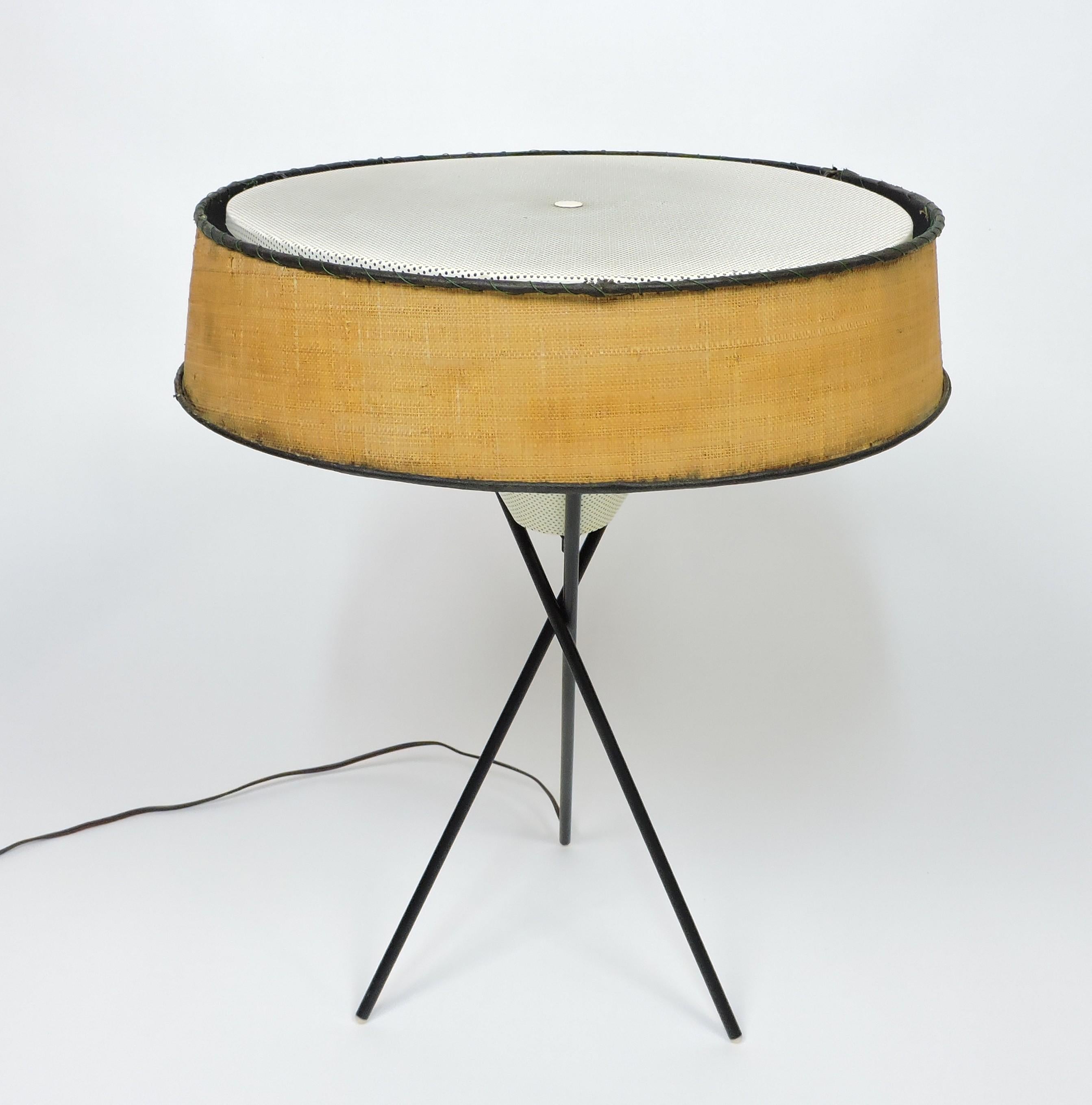 Iconic mid century 1950s tripod table lamp designed by Gerald Thurston and made by high quality manufacturer, Lightolier. This lamp has a perforated white enameled metal diffuser cone and top with a tripod black metal base. It has the original