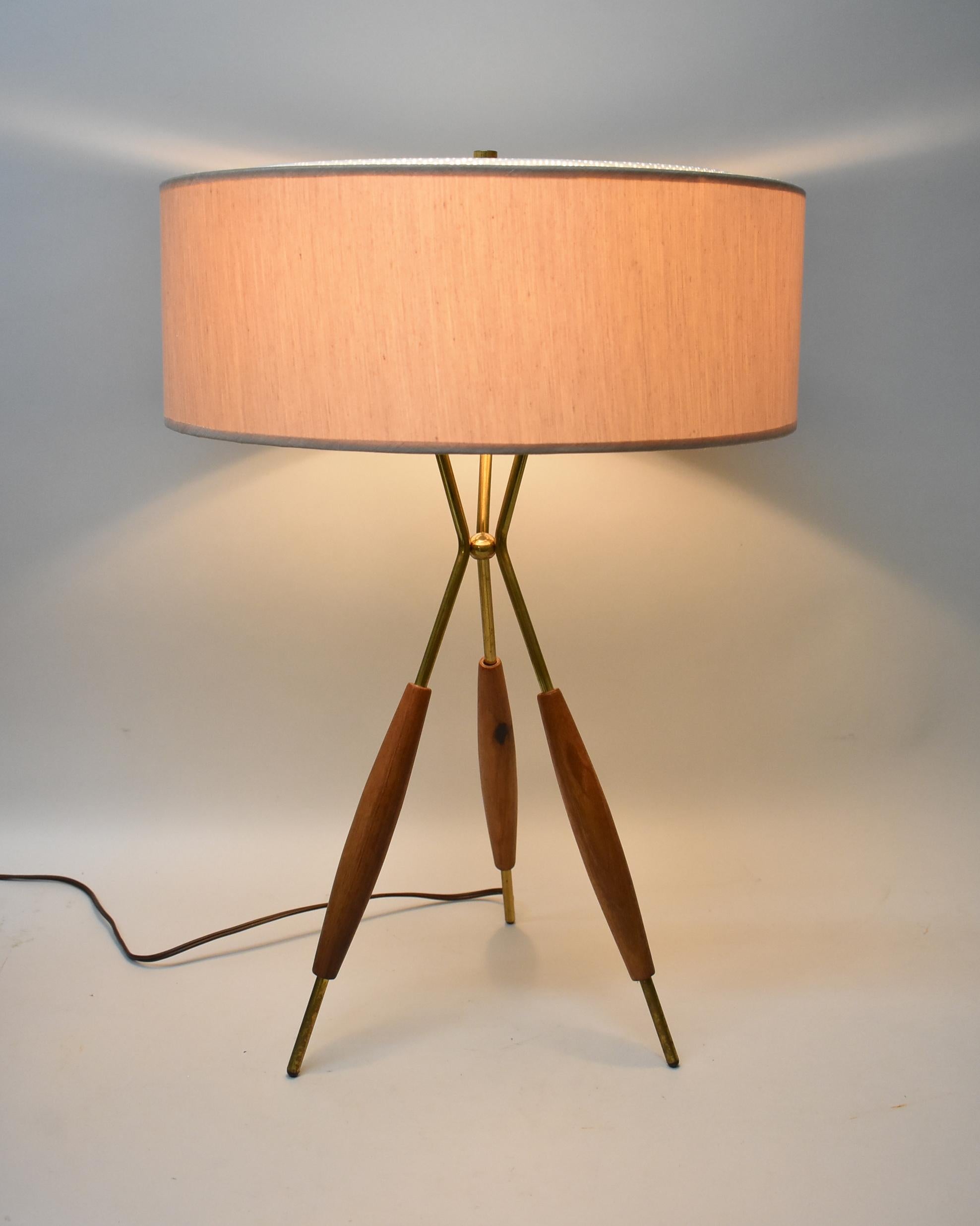 Iconic mid-century modern tripod table lamp by George Thurston for Lightolier from the 1950's. The lamp features 3 original sockets with a turn switch, 3 brass and walnut legs, and the original shade with light diffuser screen. The lamp is in