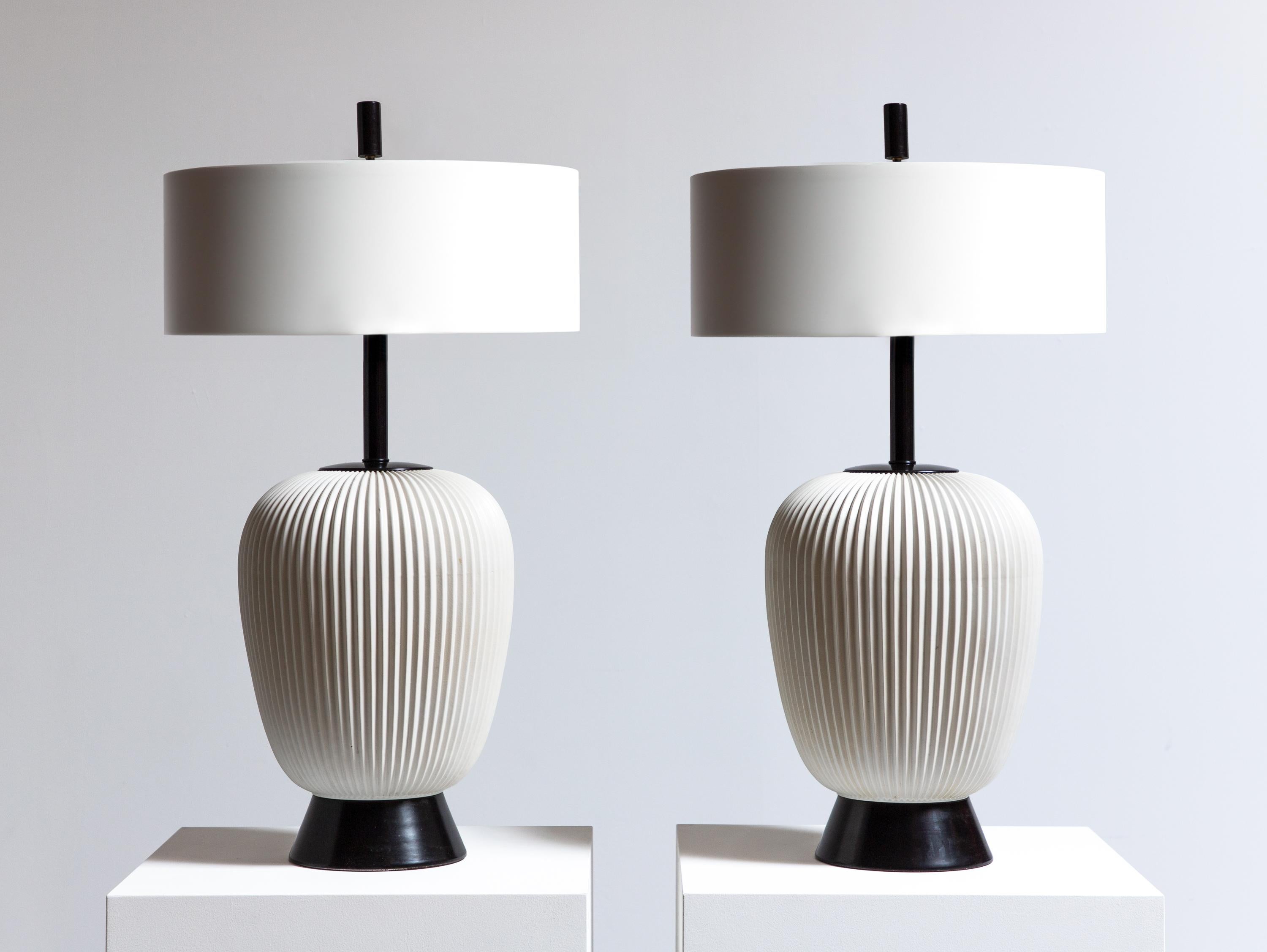 Pair of ceramic table lamps, designed by Gerald Thurston for Lightolier. Executed in a minimal black and white, this fresh design has a ribbed motif that adds texture to these large scale lamps. Finished with sleek black enameled metal accents,