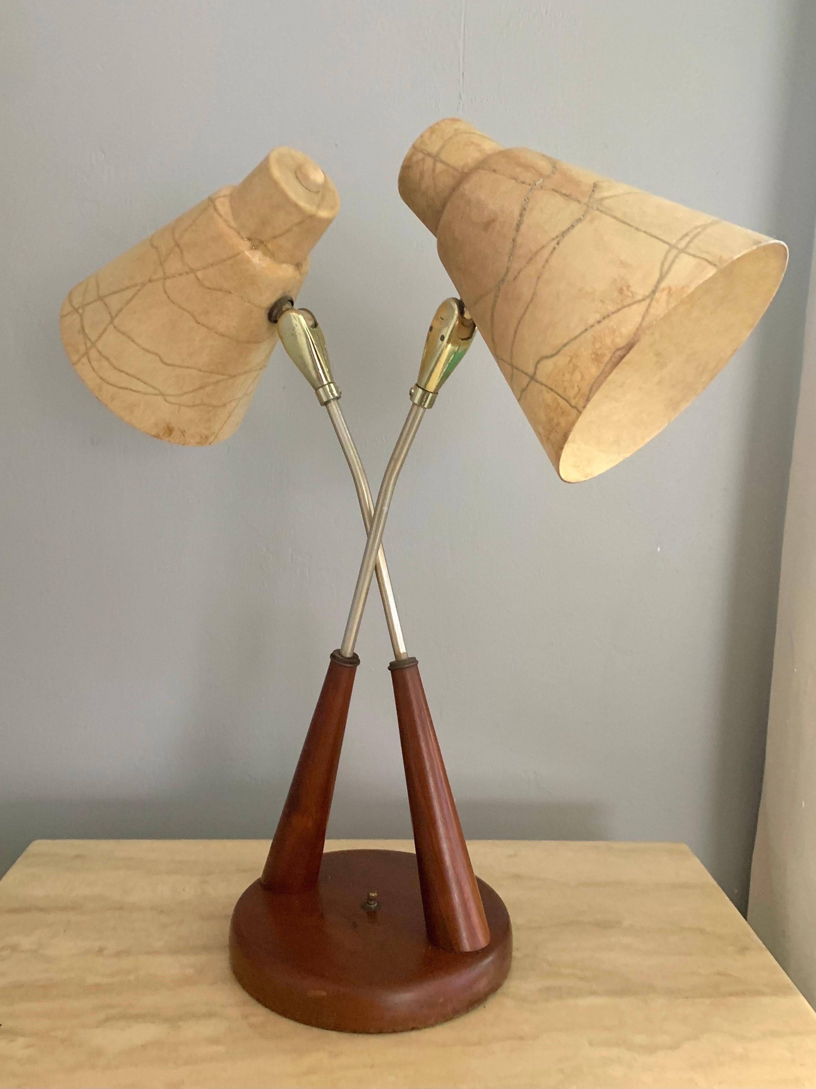 Unique double headed table lamp attributed to Gerald Thurston for Lightolier. A solid wood base and arms reaching up further with metal brass plated arms holding two lamp heads. The lamps both have an original fiberglass shade with different