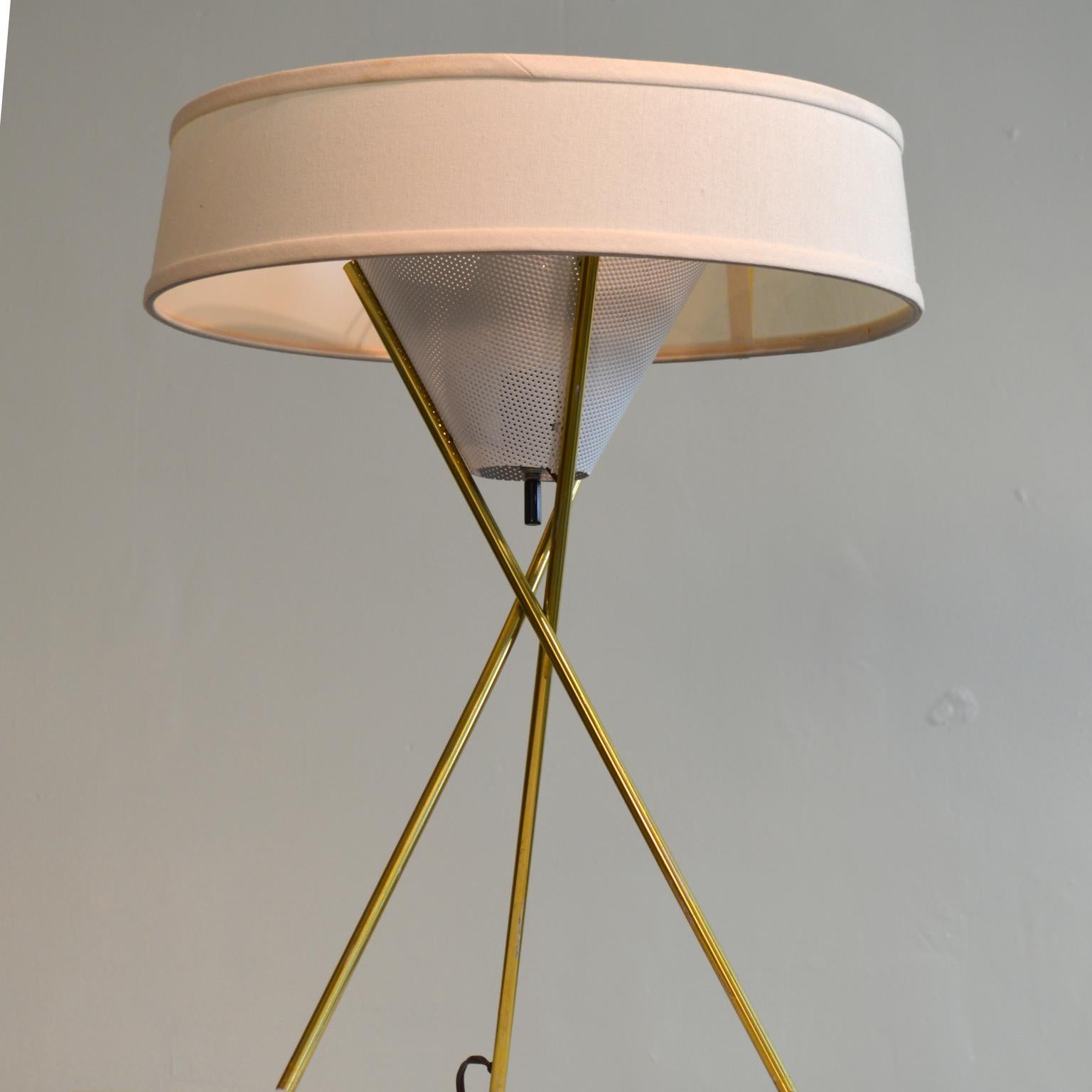 Brass tone tripod table lamp by Gerald Thurston. An elegant and much-imitated design, the three legs appear to bind together with no visible fastening, cleverly held together by the perforated metal diffuser cone. One of the legs hides the electric