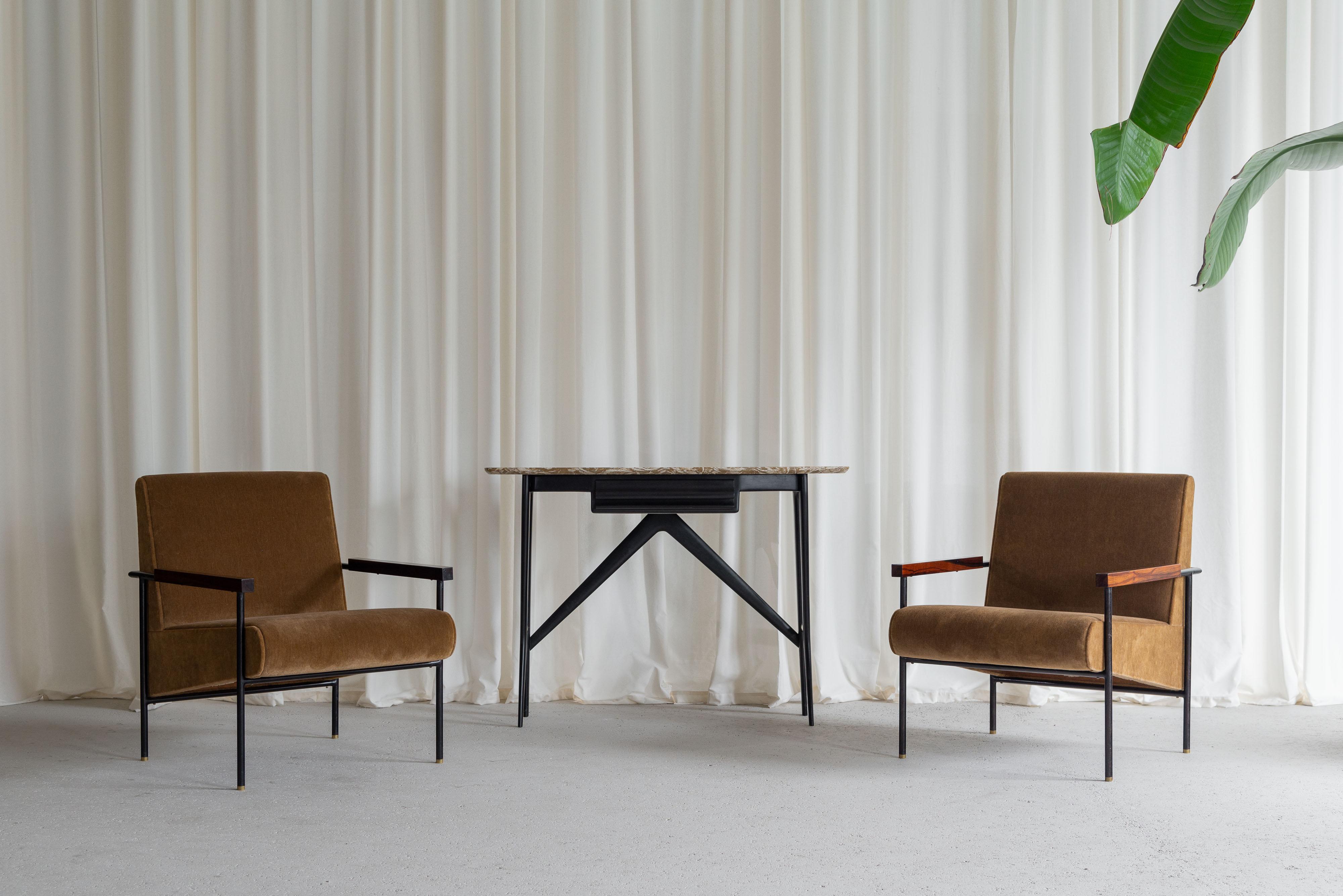 Stunning minimalistic armchairs by Geraldo de Barros and manufactured by Unilabor in Brazil, 1950. These chairs have a black painted tubular metal frame with subtle placed brass feet. On the horizontal steel structure on the front are two streched