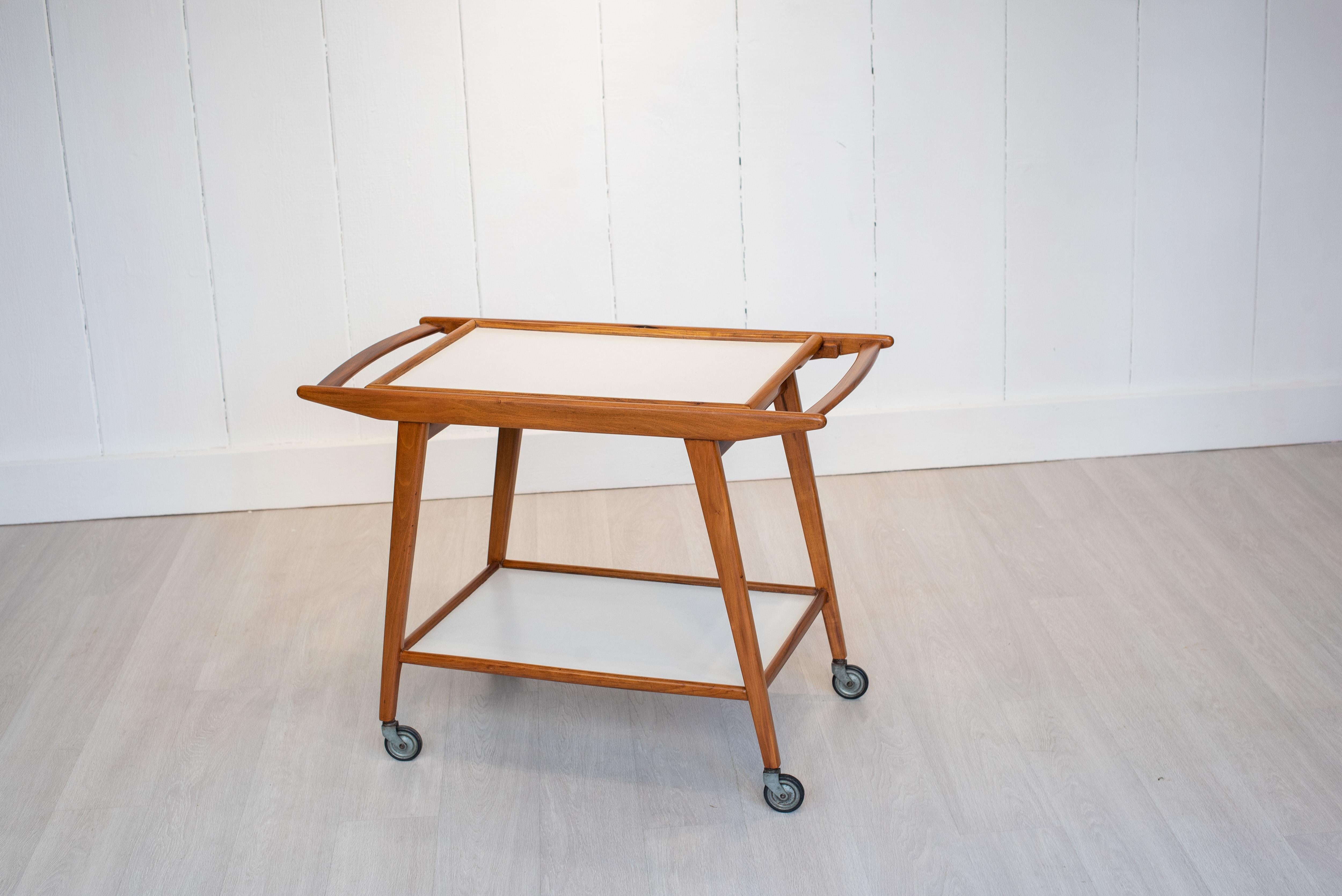 Made in the 1960s by Geraldo de Barros, this tea trolley of solid caviuna is a landmark piece of Brazilian design. The pure, fine and slightly curved lines give it a sensuality. Its white melamine trays are in perfect harmony with the wood, creating
