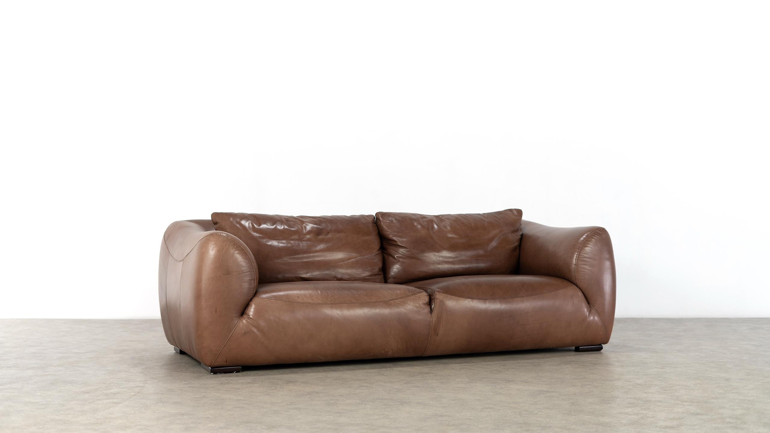 Absolutely casual and impressive 2 seater sofa in finest, chocolate - coloured leather - we attribute it to the Dutch designer Gerard van den Berg, ca. 1970.

All seams are curved, which gives the sofa its character. The back cushions are held in