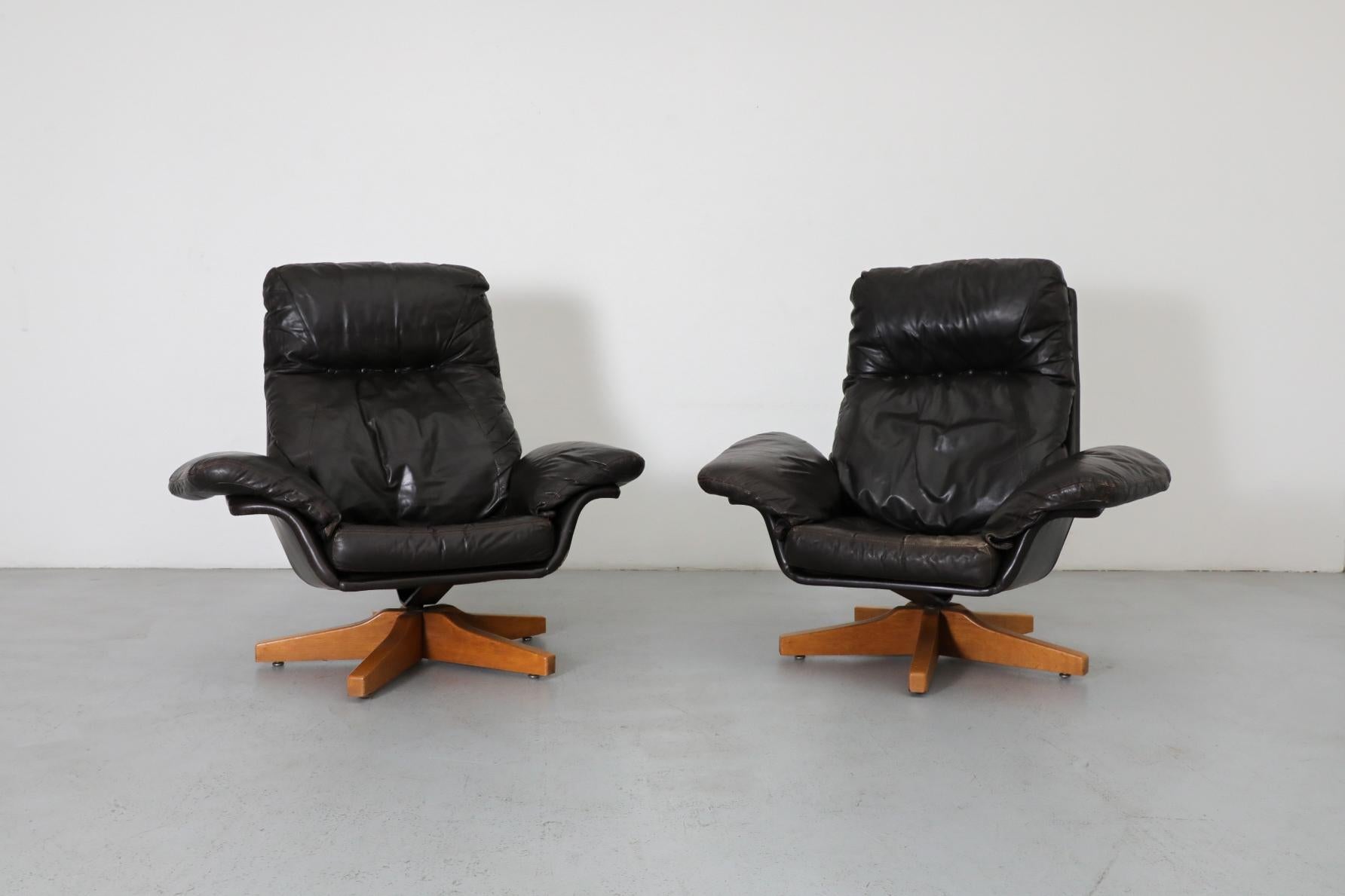 Chaise de salon pivotante en cuir brun espresso attribuée par Gerard van den Berg avec base en chêne. Il ne reste qu'une chaise, l'autre est vendue. Il est doté d'un cadre en cuir et d'un coussin amovible avec appui-tête et accoudoirs incurvés. Tous