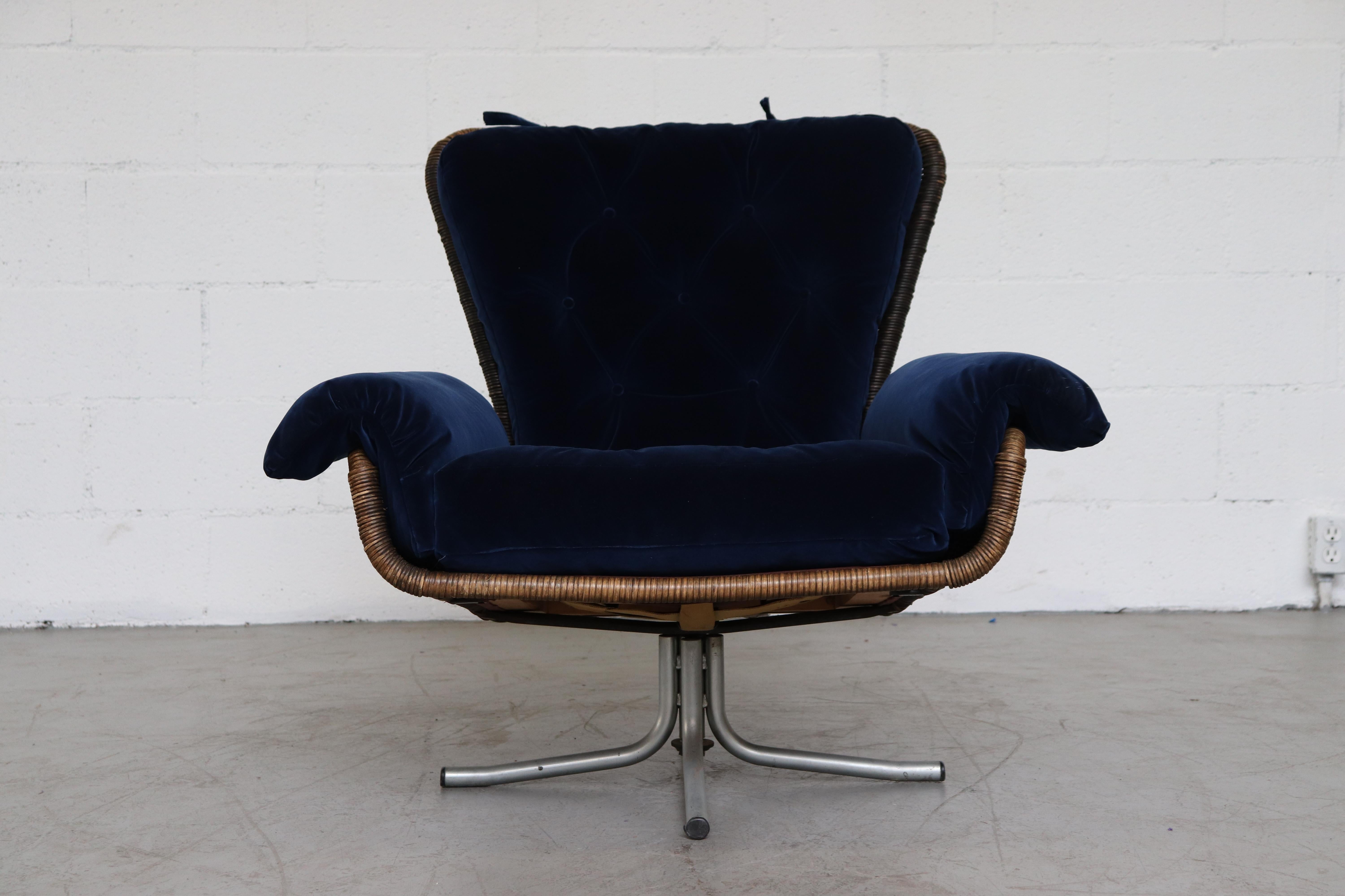 Dramatic high back rattan swivel lounge chair with new cushions in deep royal blue velvet. Woven rattan frame, originally dyed black has faded to a terrific patina. Rattan in original condition with visible signs of wear consistent with its age and