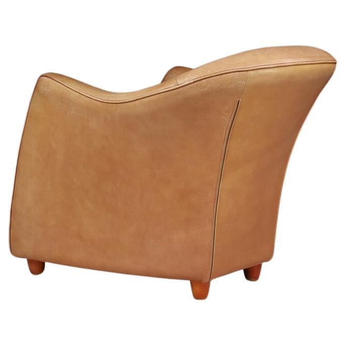 Gerard van den Berg lounge chair in a stunning cognac leather for label. This is a soft form lounge chair in its original condition with visible patina and scratches to leather that is honestly in excellent condition we think. This chair is unique