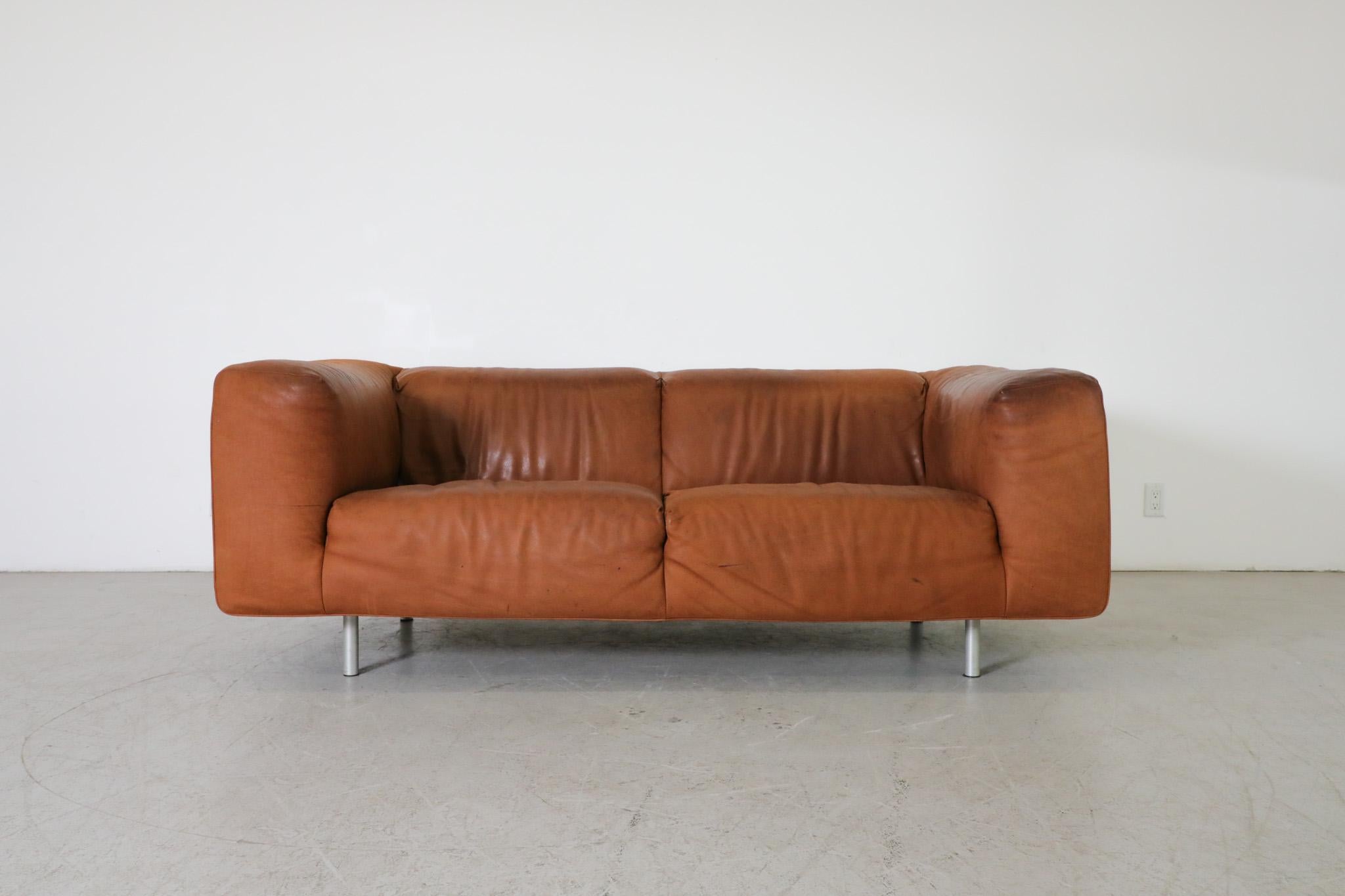Handsome Cognac leather sofa with aluminum chrome legs by Gerard van den Berg. A comfortable Soft structure leather sofa with some visible wear and patina. Some visible staining and sun fading as well as some loose stitching on the right top corner.