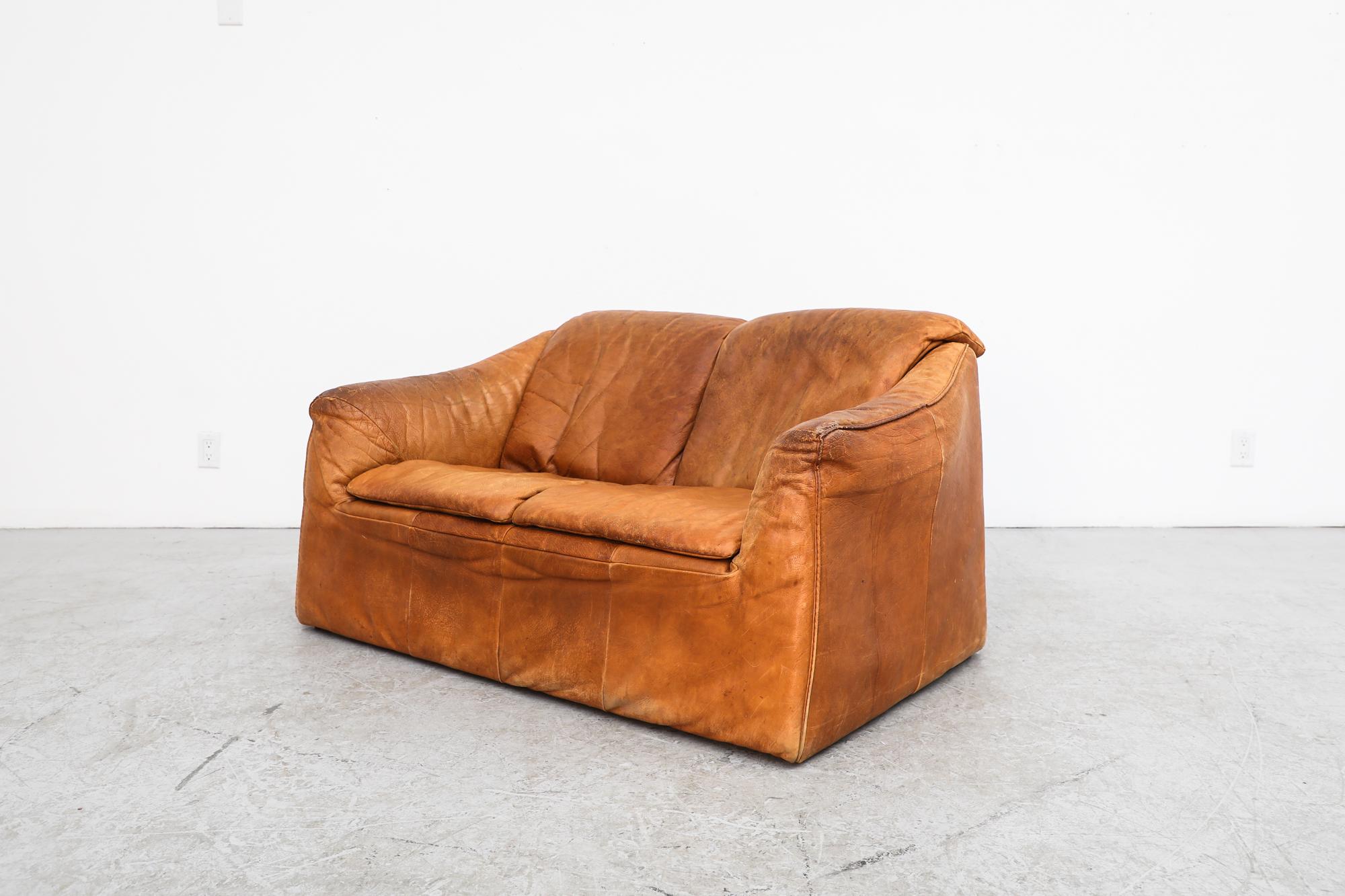 Cognac leather loveseat designed by Gerard van den Berg for Montis. In original condition with visible wear, including heavy patina on leather and some loose stitching. Wear is consistent with its age and use.