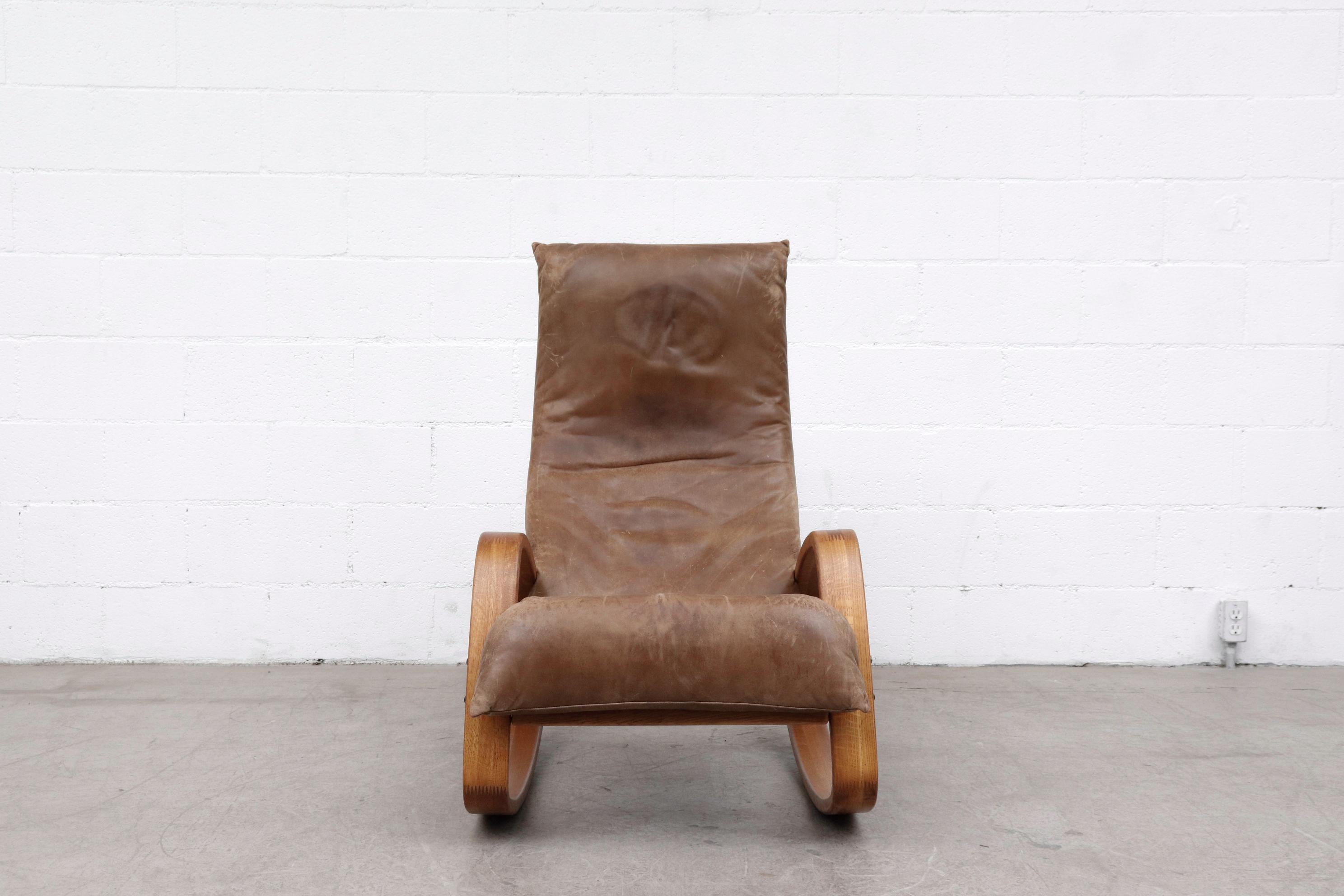 Midcentury Gerard Van Den Berg high back natural leather rocking chair with bent oak elliptical legs. Leather and frame have visible patina. In original condition with wear consistent with age and use.