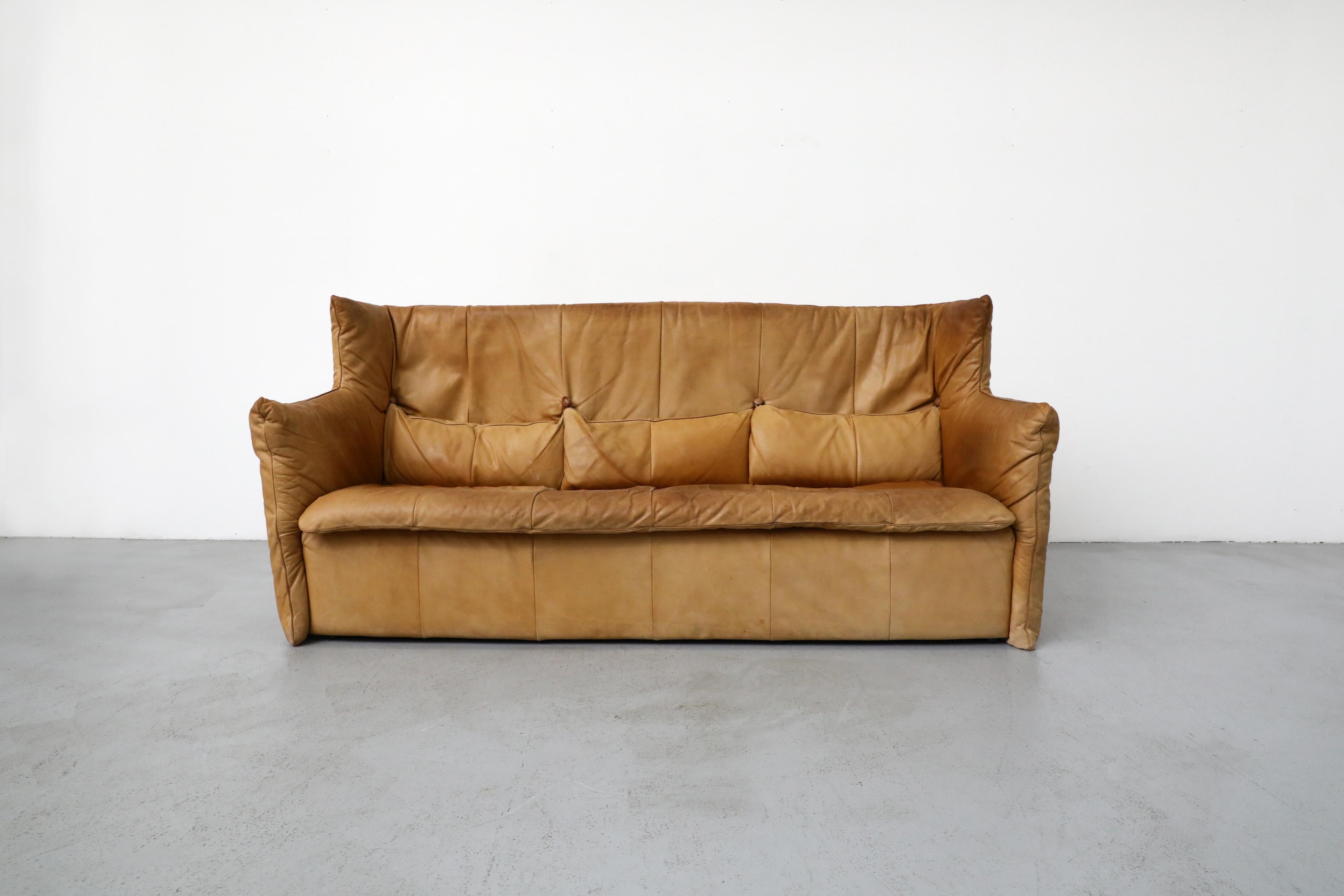 Canapé à haut dossier en cuir naturel, créé par Gerard van DEN Berg pour Montis. Cuir magnifiquement usé avec 3 coussins de dos assortis qui s'attachent à de superbes boutons tressés en cuir. En état original avec une usure conforme à son âge et à