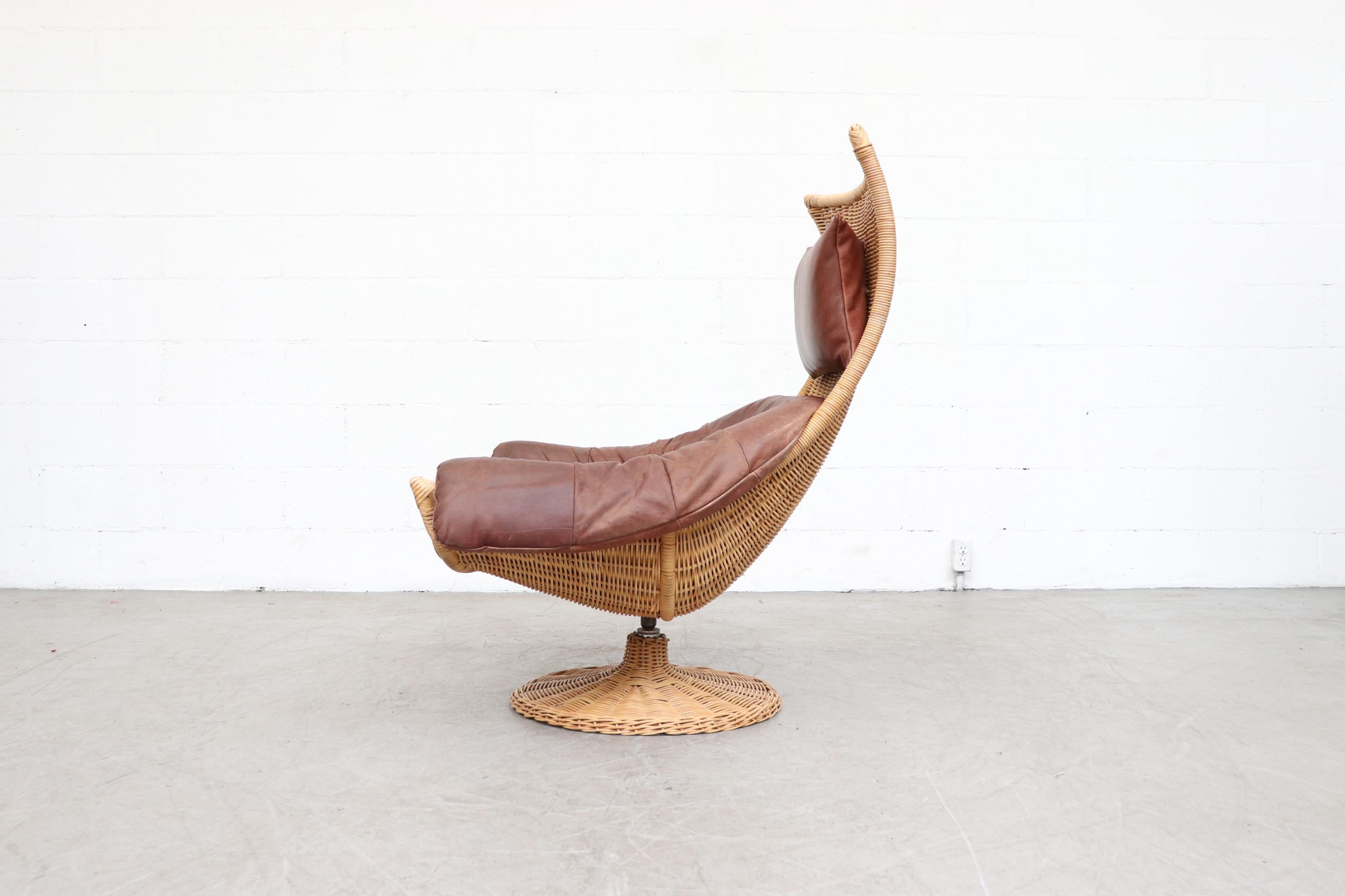 Gerard Van Den Berg swivel lounge chair. Natural woven rattan frame contrasted beautifully with rust leather cushion and headrest. In original condition with some visible wear consistent with age and use.