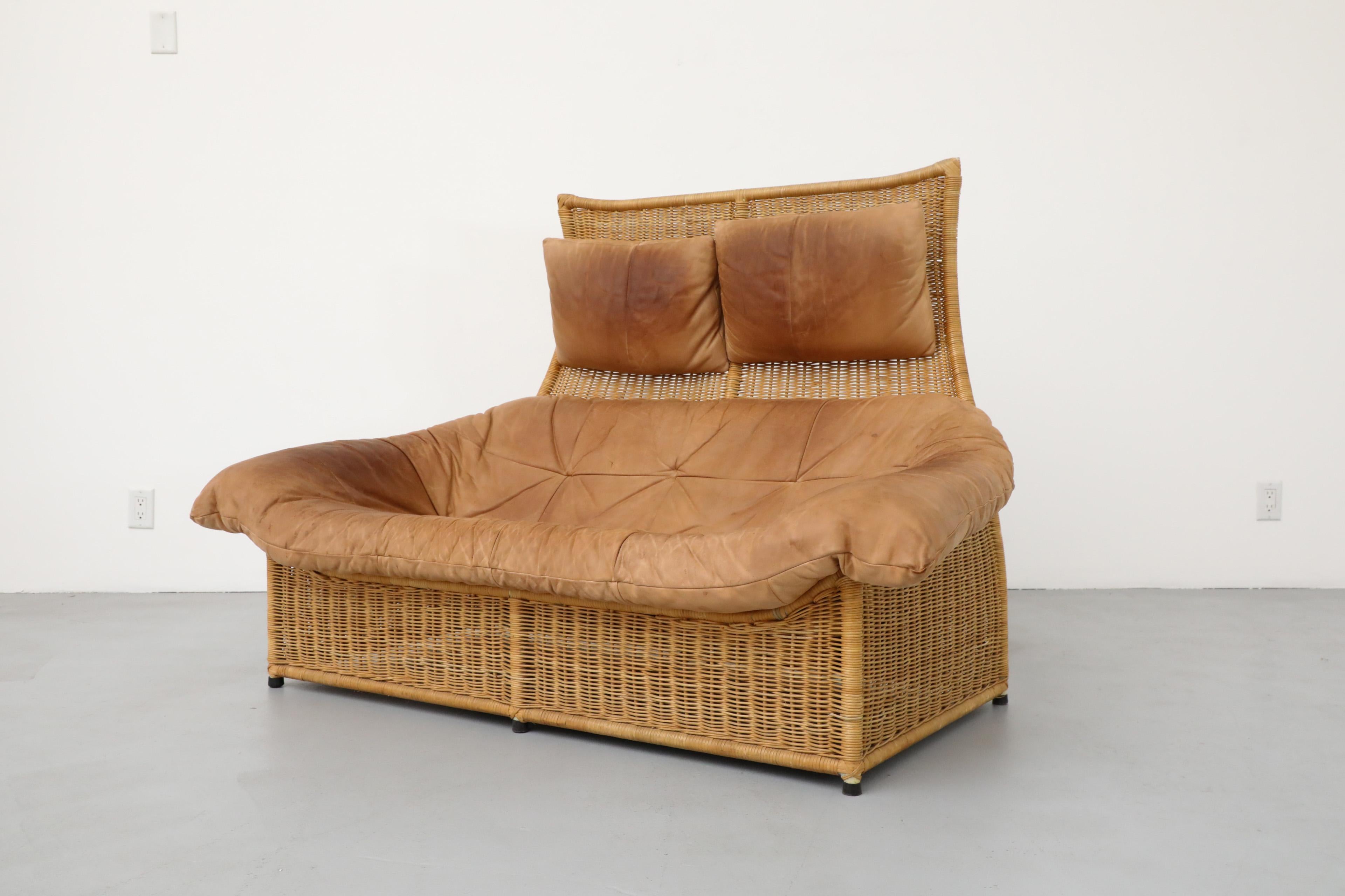 Beautiful loveseat with buck leather seating and hanging headrest pillows on a rattan frame designed by Gerard van den Berg for Montis. The leather has beautiful patina. In original condition including minor rattan breakage, discoloration and