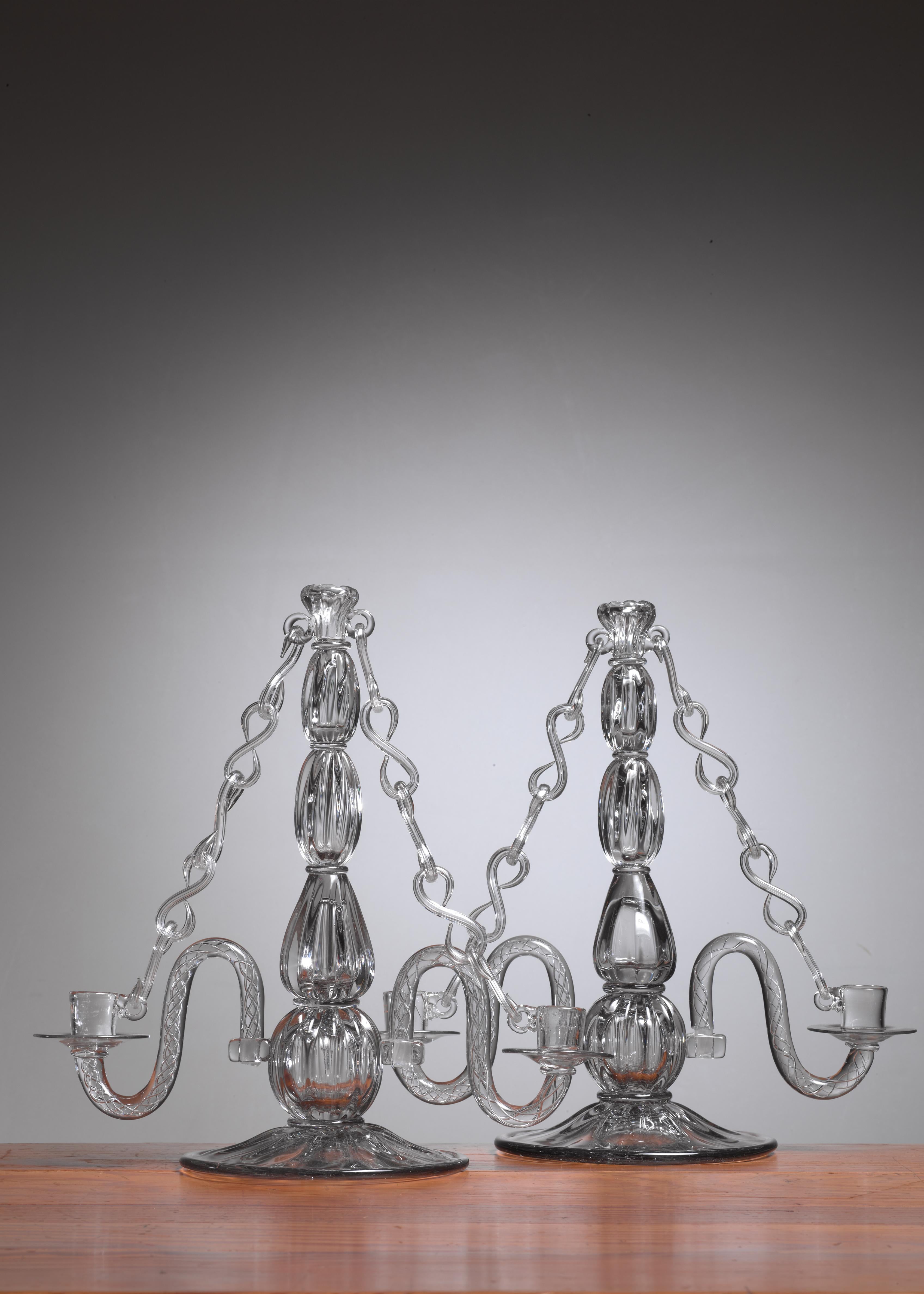 A pair of glass candelabra, designed by Gerda Stromberg and executed by Masterblower Knut Bergqvist for Strömbergshyttan Glassworks in 1941. The candelabra can hold three candles, one on top and two in the lower cups. The lower cups with their