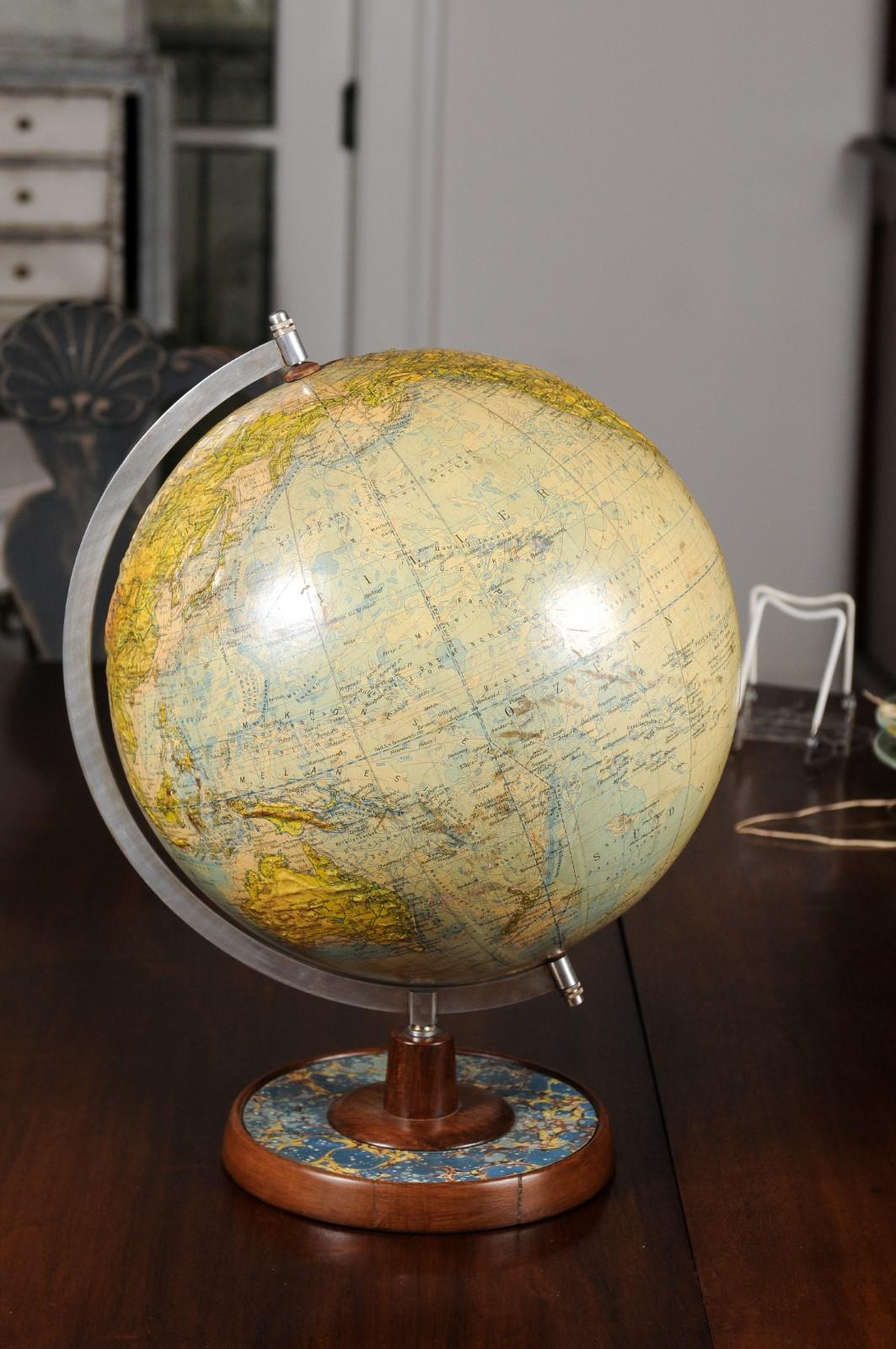 A German terrestrial globe from the late 19th century, raised on a circular wooden base with marbleized paper décor and metal protractor. Born in Germany during the last decade of the 19th century, this terrestrial globe is signed Professor Dr.
