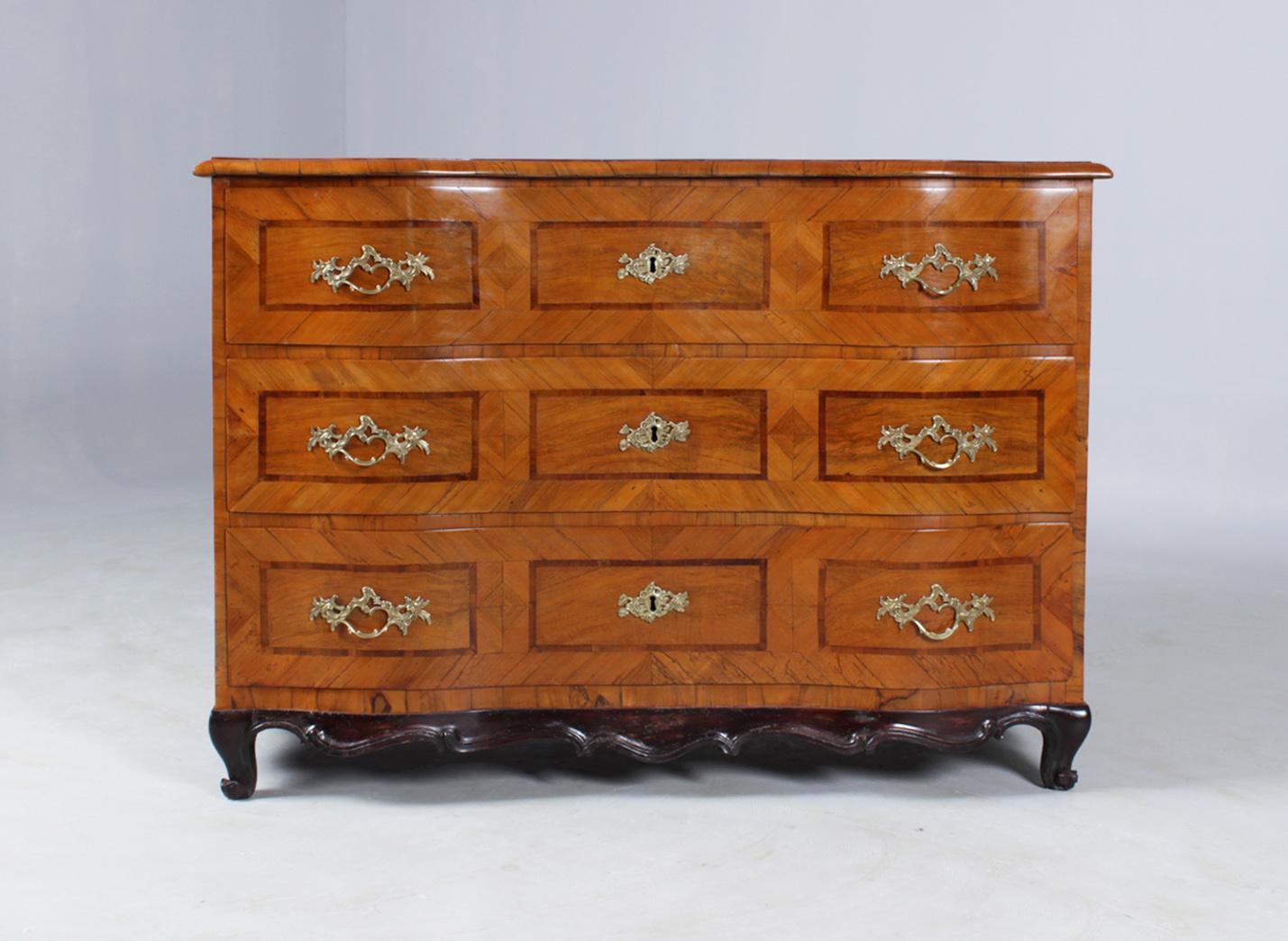 Dimensions: H x W x D: 86 x 123 x 70 cm.

Antique chest of drawers in walnut veneer with banded plum inlays. Three large lockable drawers with brass handles and fittings.

The chest of drawers was made in the Mainz region. Typical for the time