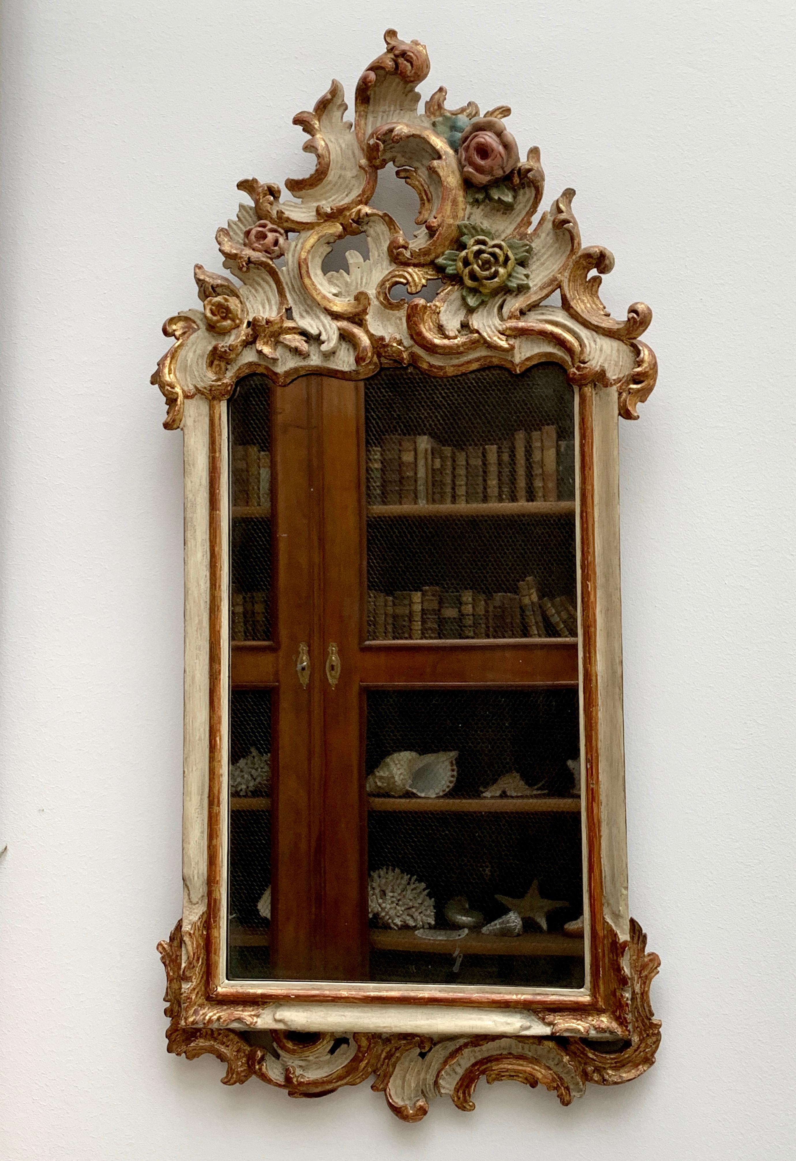 Très charmant miroir Rococo allemand du 18ème siècle. Magnifiquement sculpté de c-scrolls et de boutons de fleurs, peint en blanc et polychrome. Plaque de miroir antique et dos original.