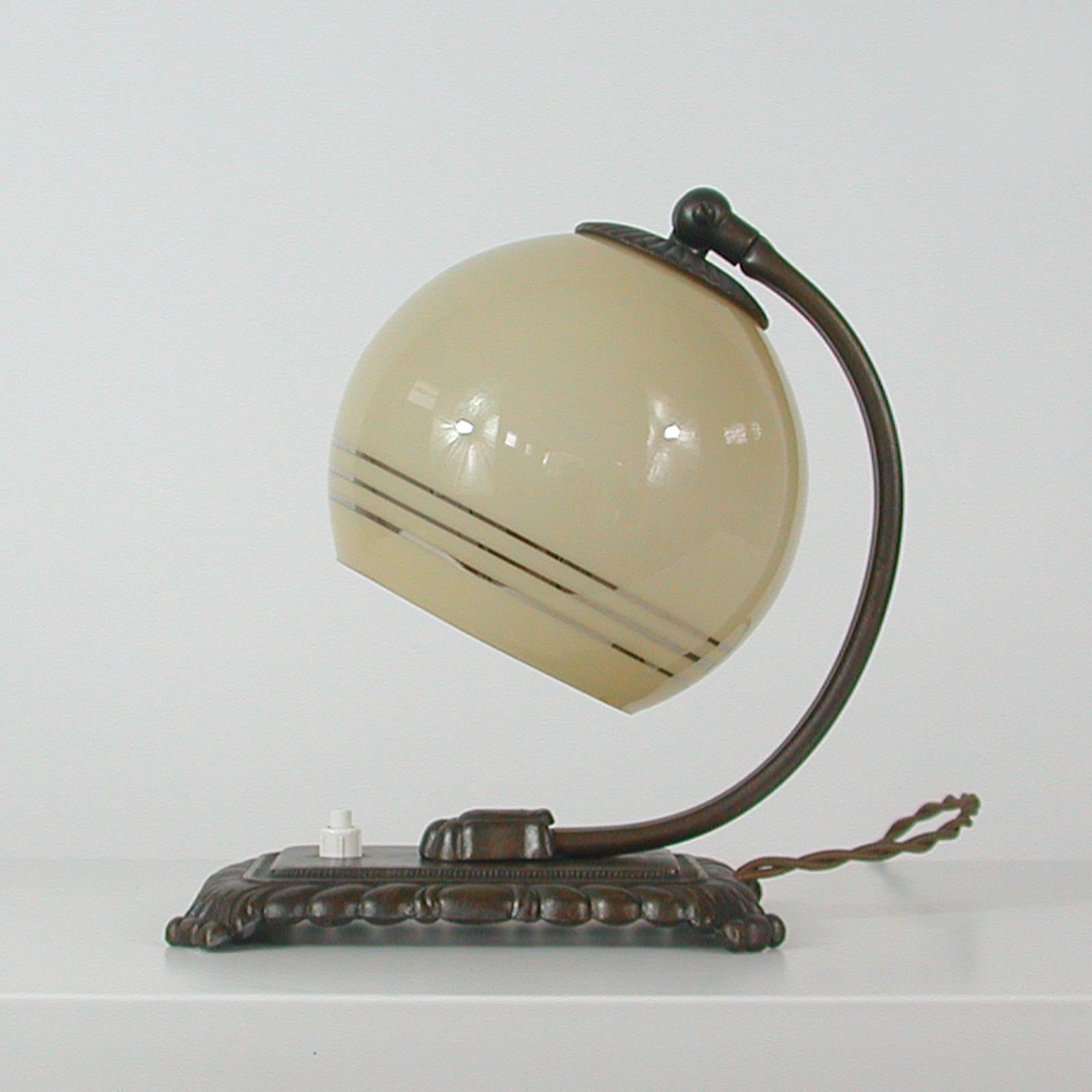 This awesome vintage table or bedside lamp was made in Germany in the 1920s-1930s during the Art Deco period. It is made of bronzed brass and has got an adjustable lamp shade in cream with silver rings.

The light can be used as a table lamp as