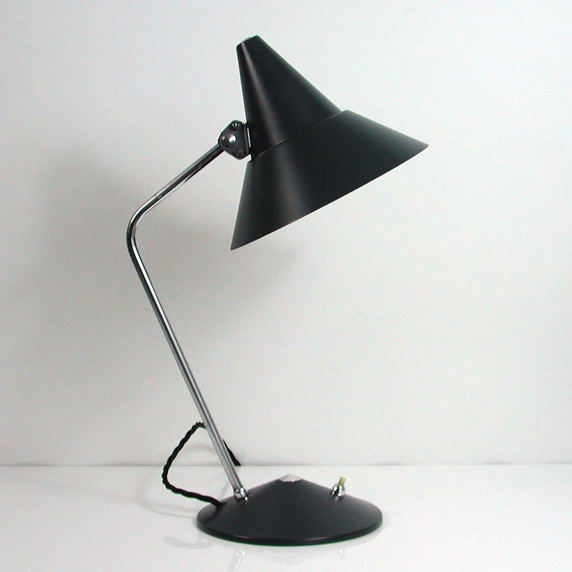 This desk lamp was designed and manufactured by HELO Leuchten in the 1950s. It features a dark grey lacquered metal lampshade and base and chrome lamp arm with adjustable lampshade.

The lamp has been newly rewired with black fabric cord and is in