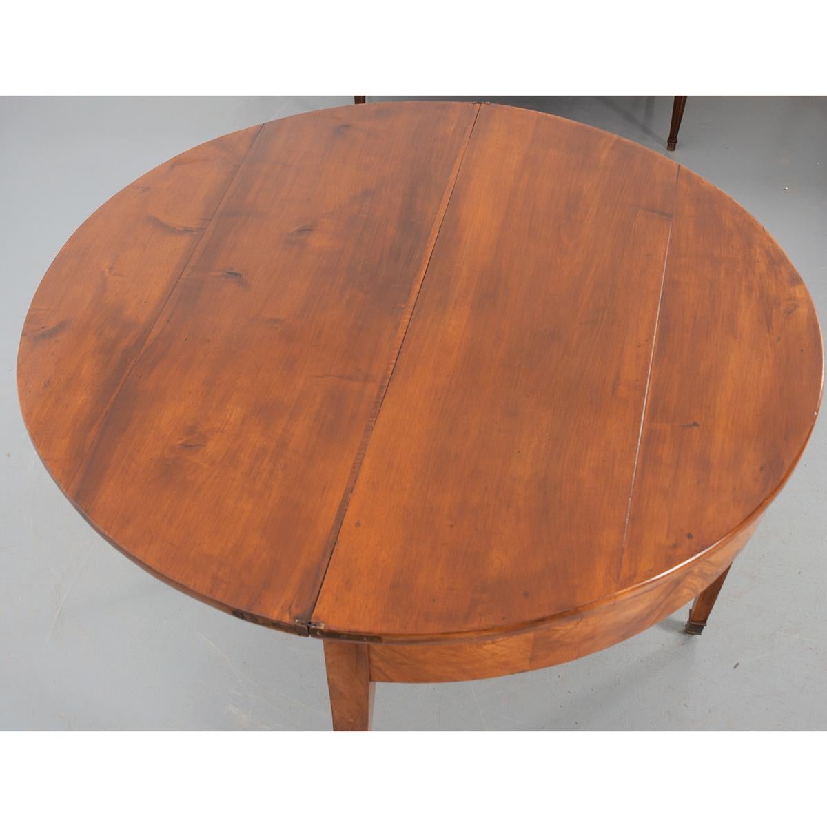 This is a great Biedermeier-style demilune table from Germany. The table has a solid, folding top with brass hinges sitting over a book-matched apron. A fourth leg is attached to a drawer that pulls out to support the top and has a felt edge as not