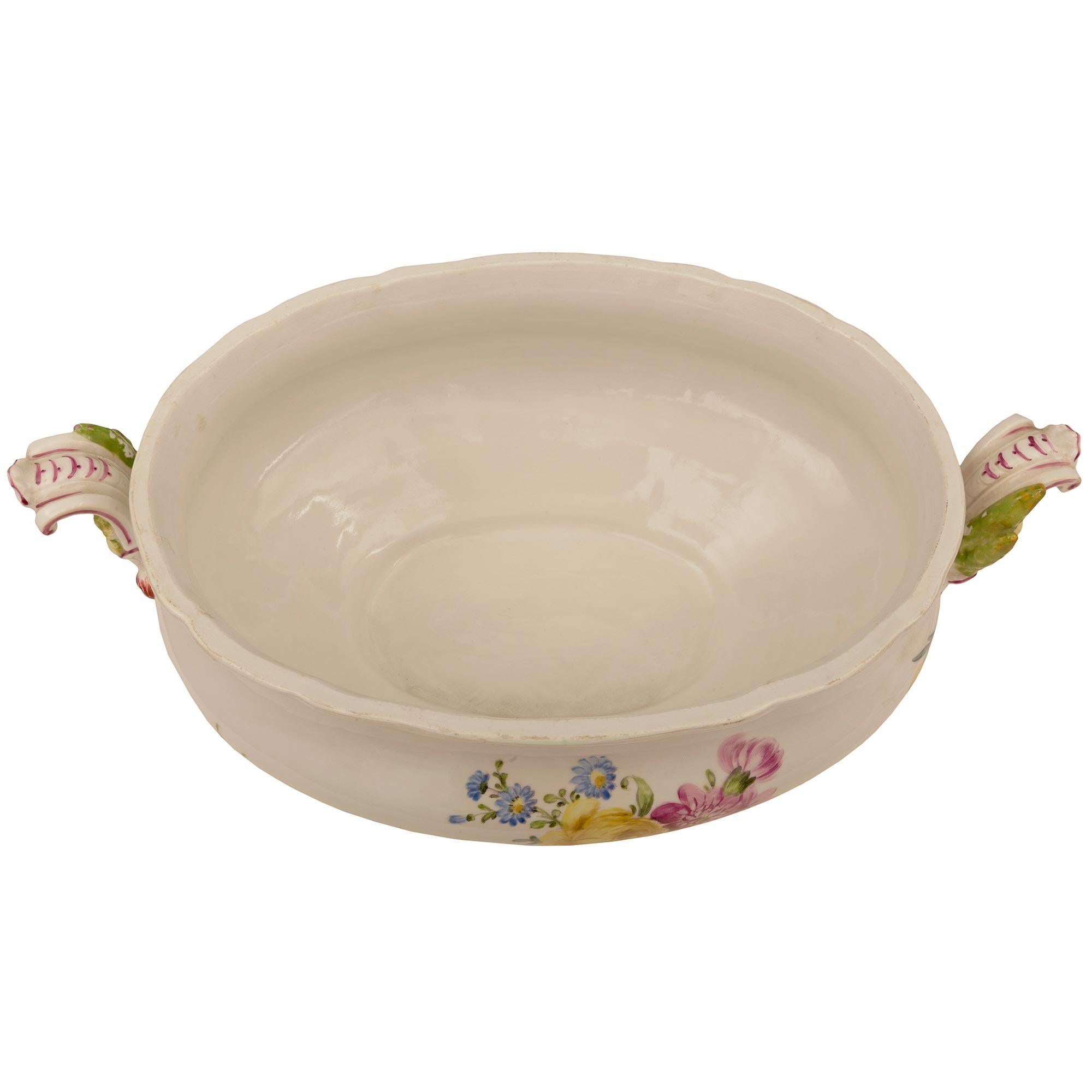 A charming German 19th century Meissen Porcelain lidded tureen. The oblong shaped tureen displays beautiful finely detailed hand painted blooming flowers with vivid colors throughout and lovely scrolled handles at each side. Above is a charming